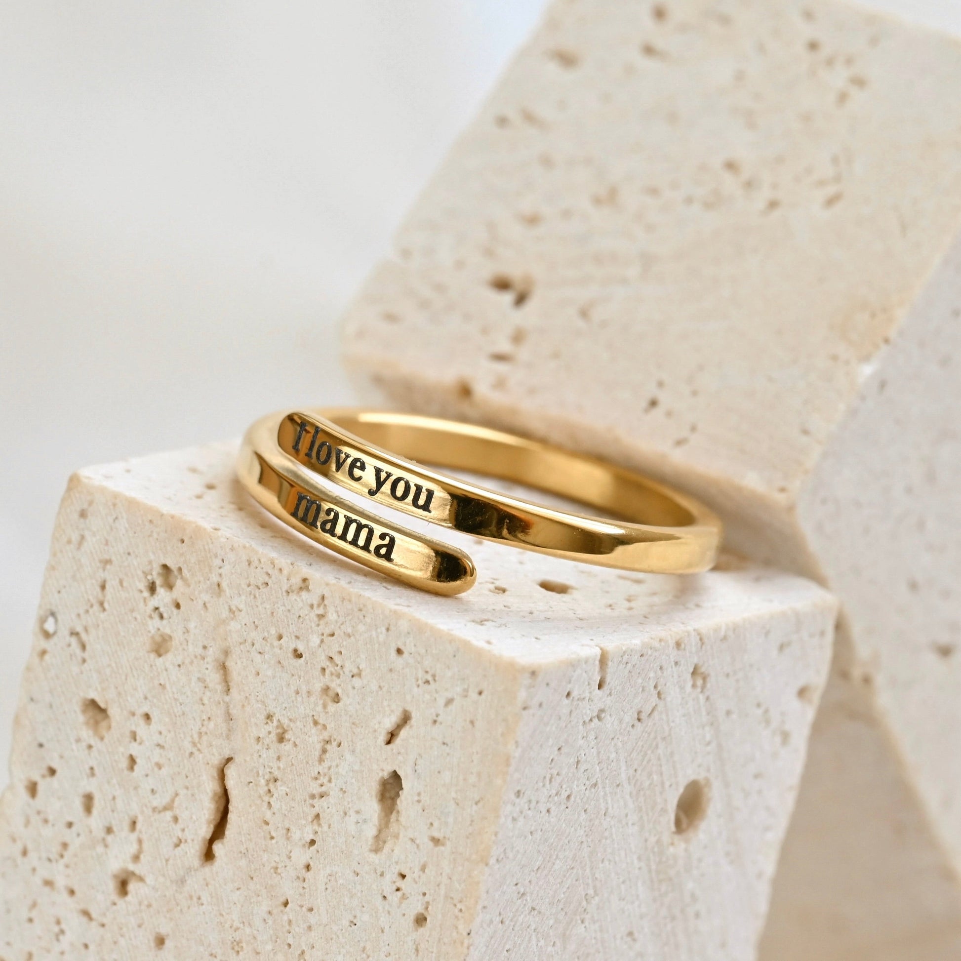 Gold ring with 'I love you mama' engraving on a stone surface