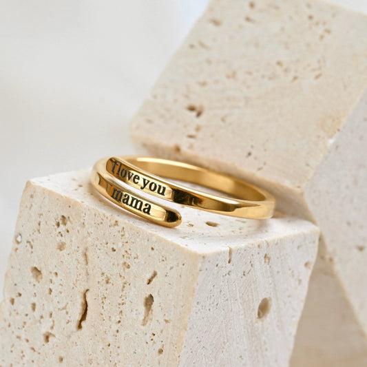 Gold ring with 'I love you mama' engraving on a stone surface