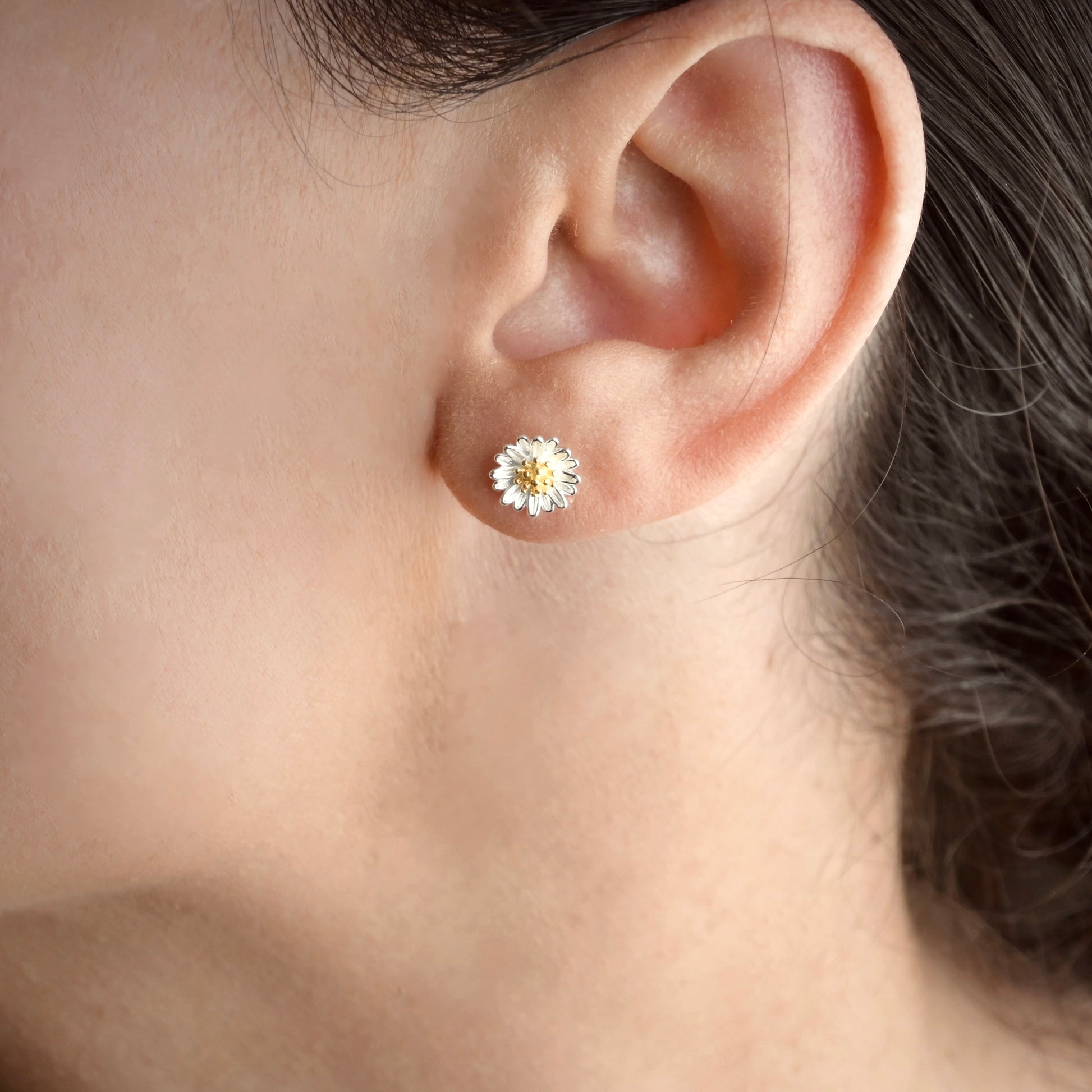 Close-up of an ear wearing a floral stud earring.