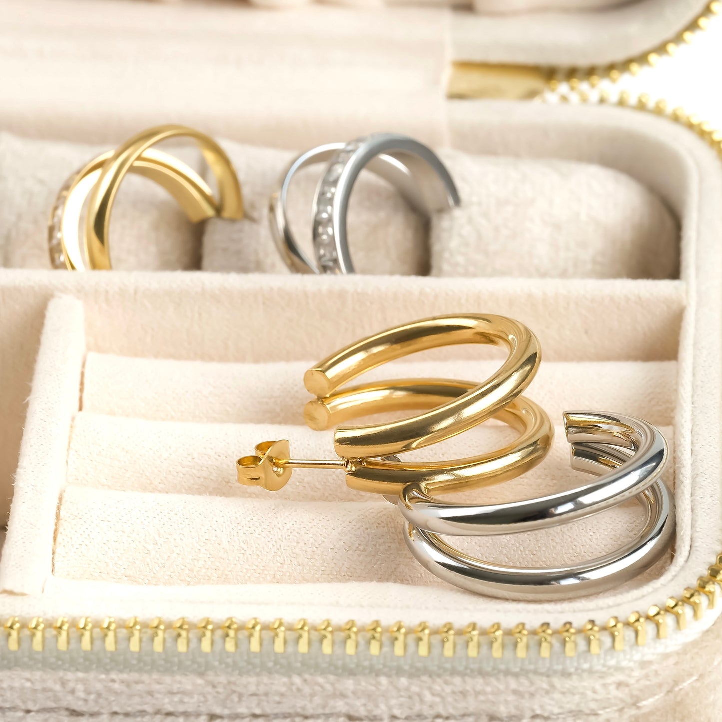 Gold and silver split hoop earrings in a beige jewelry box