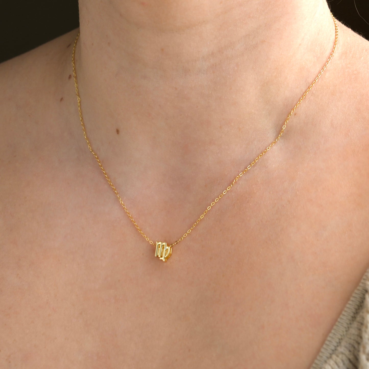 Gold zodiac necklace with a virgo symbol on a person's neck