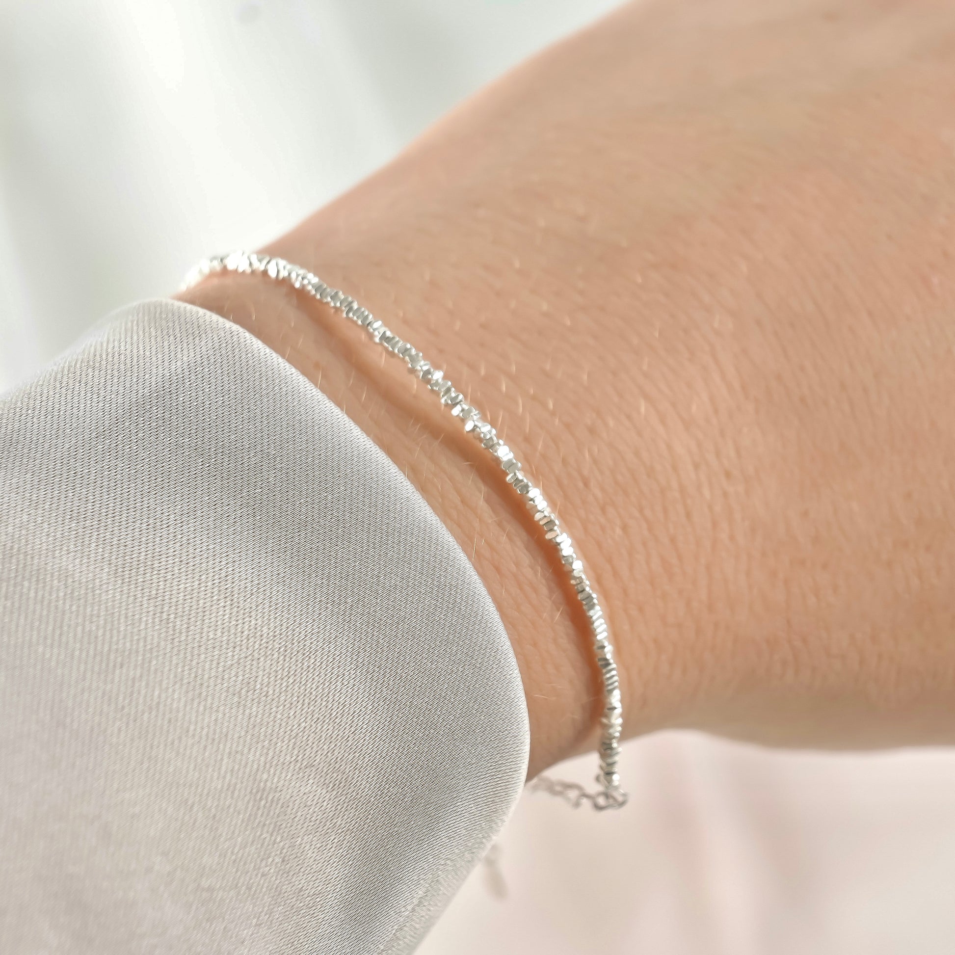 Silver beaded chain bracelet on a wrist under direct sunlight