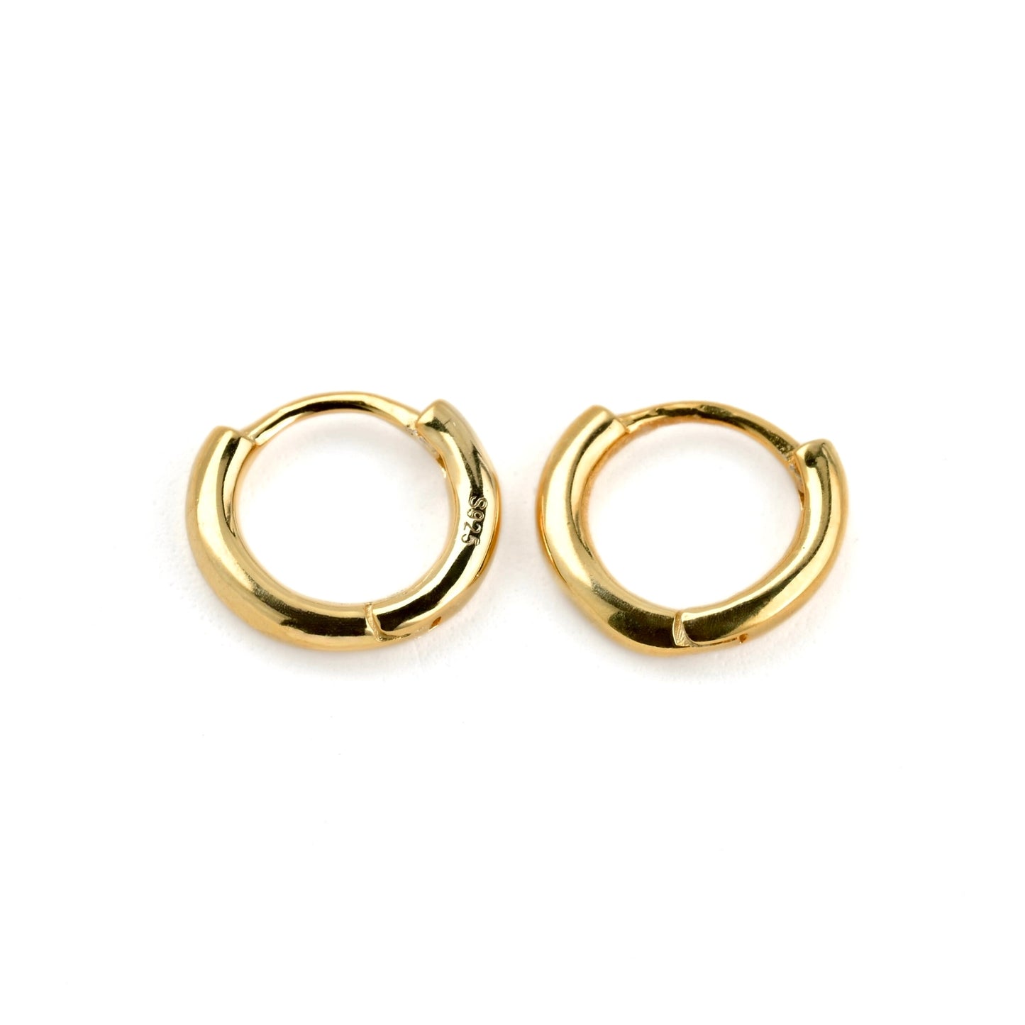 Pair of tiny gold huggie earrings on a white background