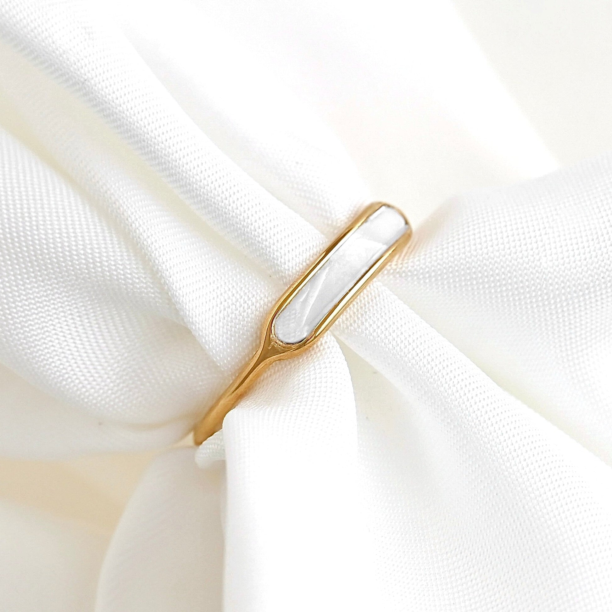Dainty gold ring with mother of pearl inlay on white fabric