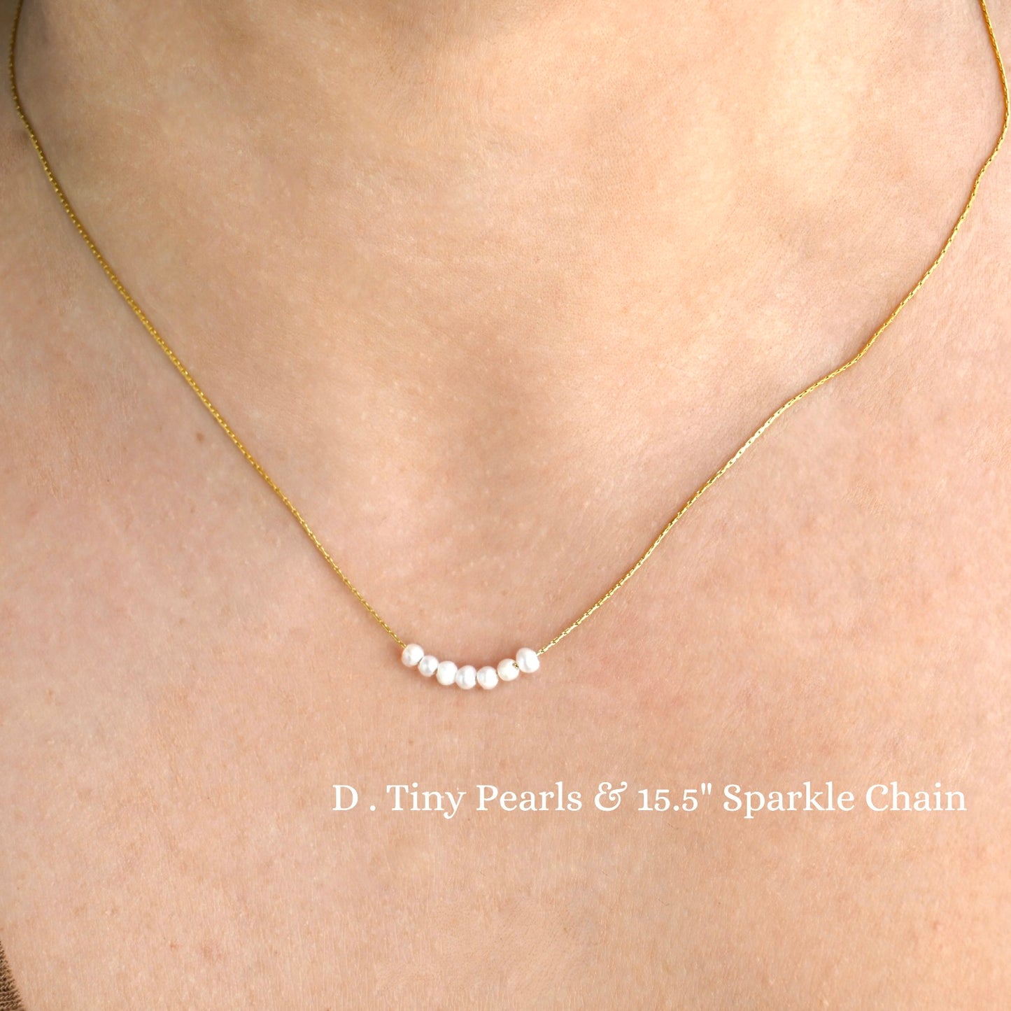 Dainty gold necklace with tiny pearls and 15.5-inch sparkle chain on a person's neck.