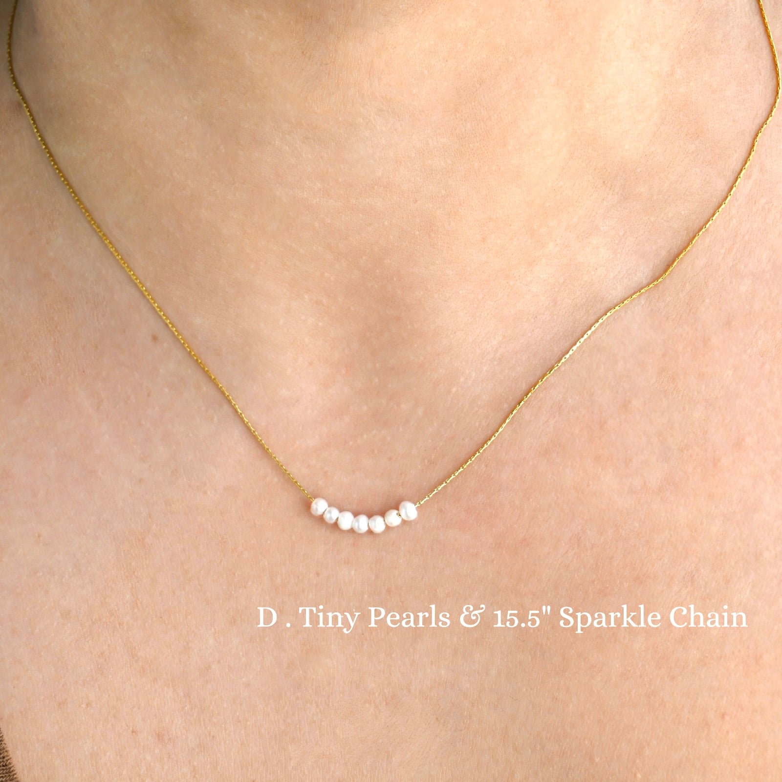 Dainty gold necklace with tiny pearls and 15.5-inch sparkle chain on a person's neck.