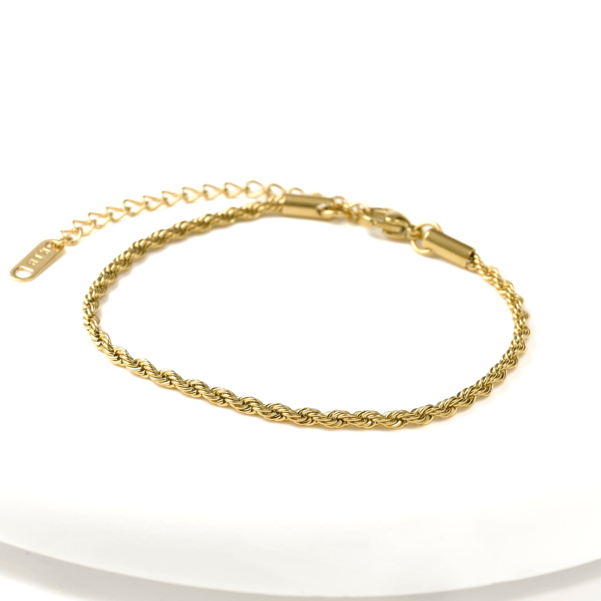 Front view of gold twisted rope bracelet  with a lobster claw clasp, extender and K18 plating hallmark tag on a white background