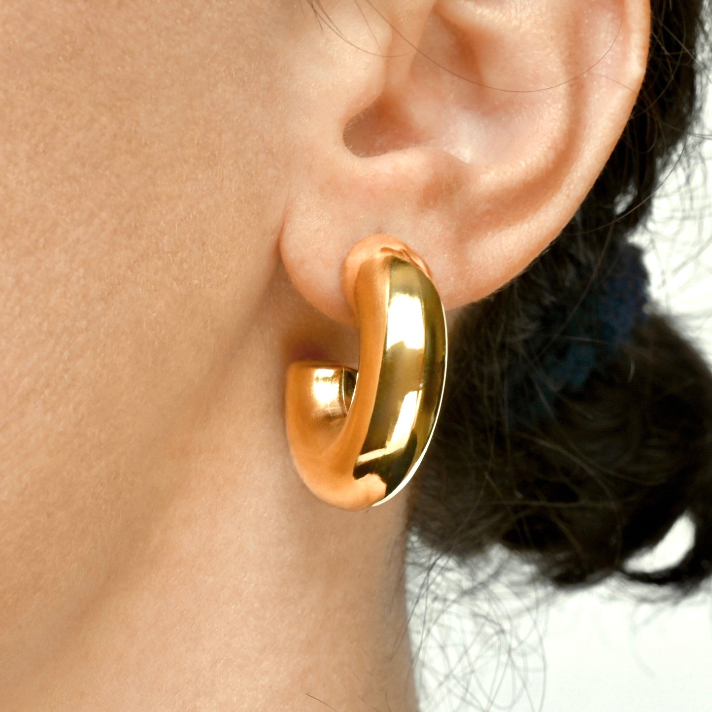 Ultra chunky lightweight hoops worn on an ear with a neutral background