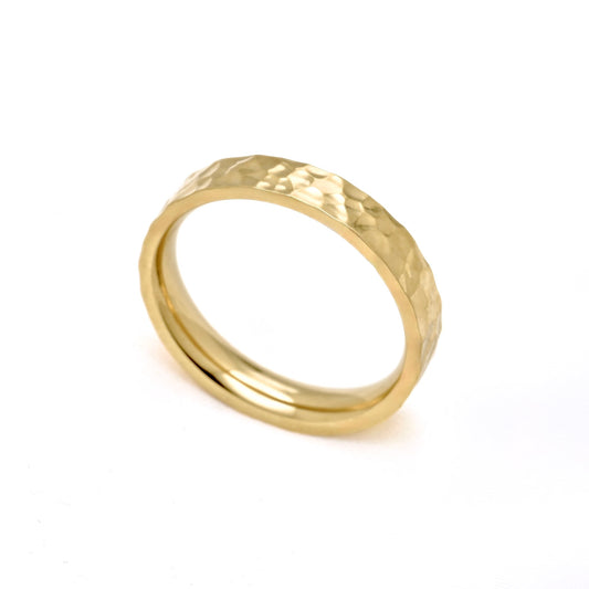 A gold band ring with a hammered textured exterior and a smooth polished interior, shown on a plain white background.