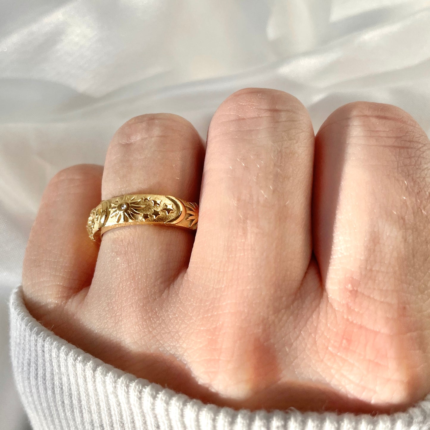 Bohemian gold ring on a finger with a white background