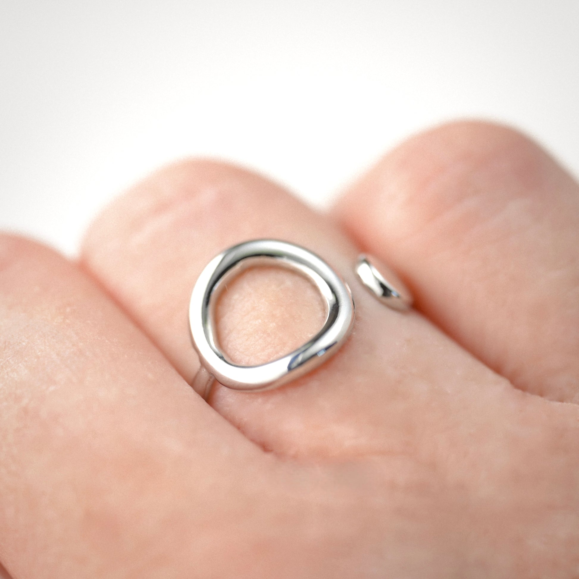Silver geometric ring on a finger with a plain background