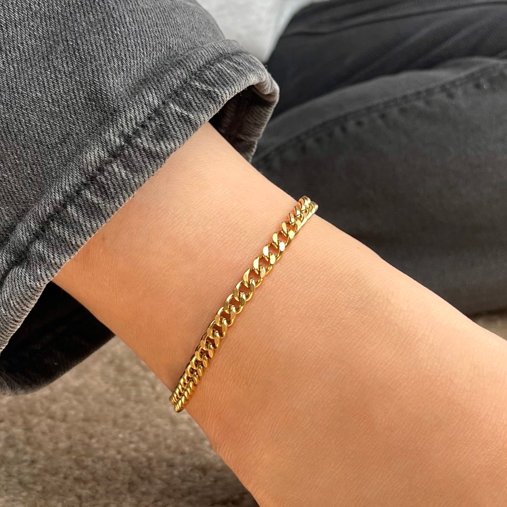Gold cuban ankle bracelet in 5mm width on an ankle with a blurred background