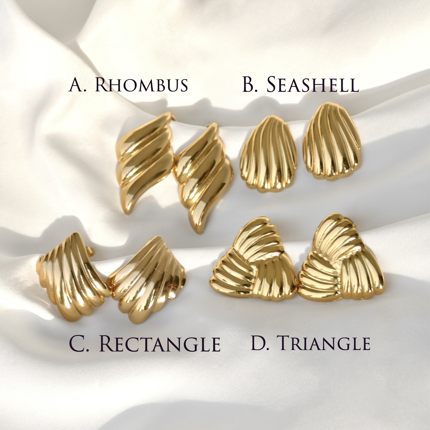 Gold earrings with rhombus, seashell, rectangle, and triangle designs on a white fabric background.