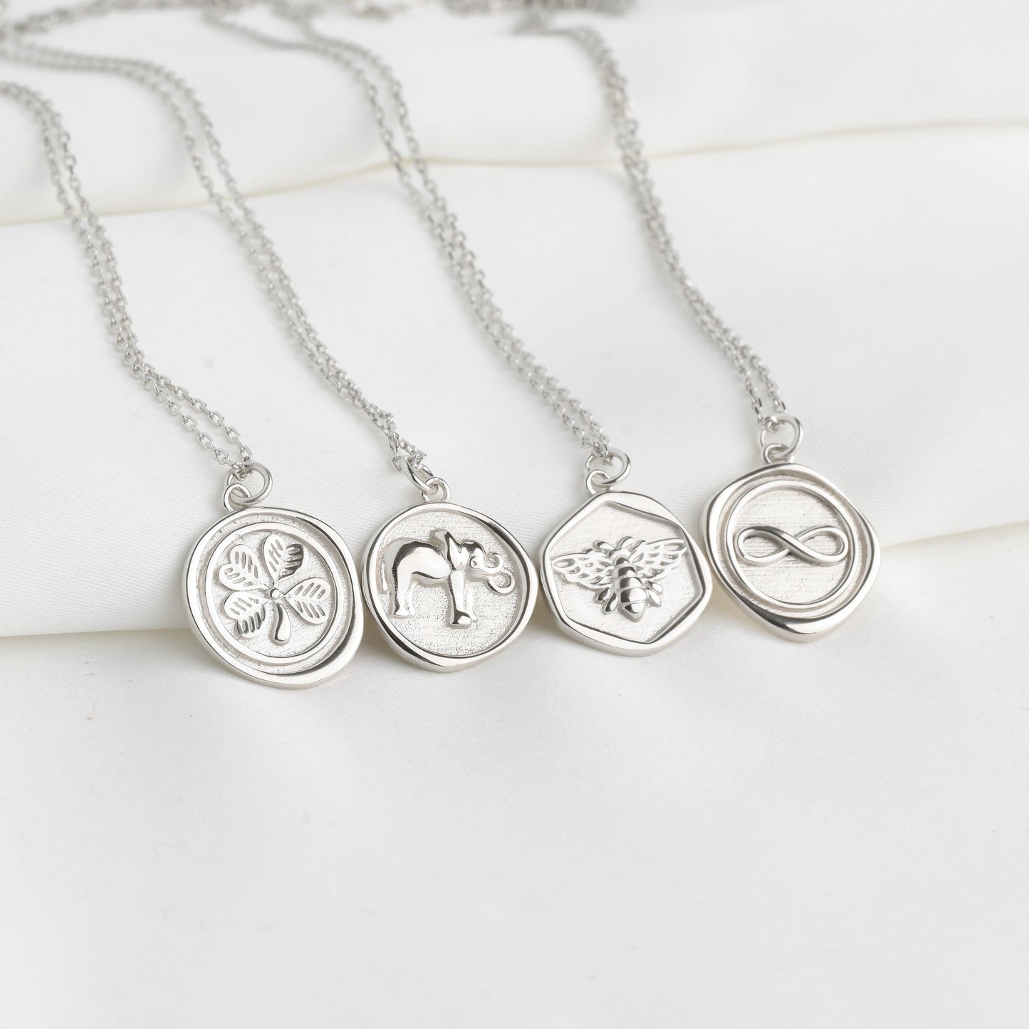 Silver necklaces with circular pendants on a light wooden surface