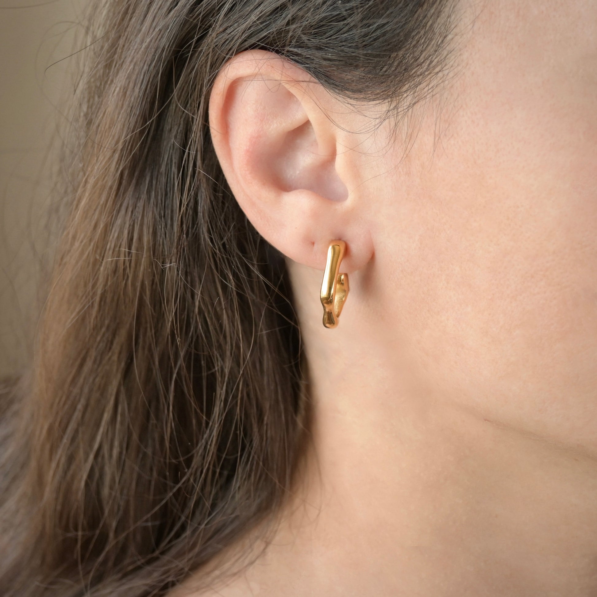 Gold hoops worn by a person with brown hair.