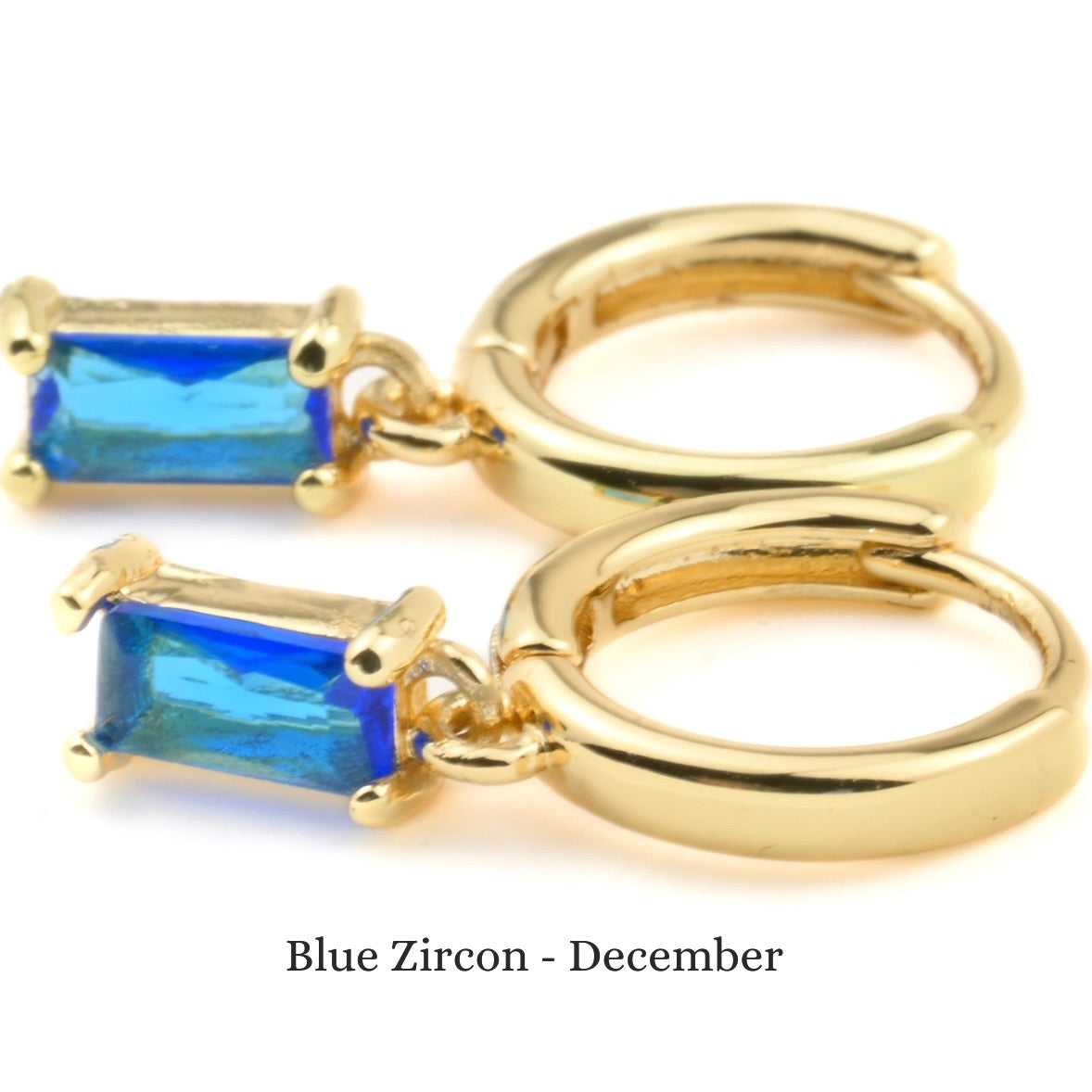 Gold hoop earrings with blue zircon stones on a white background