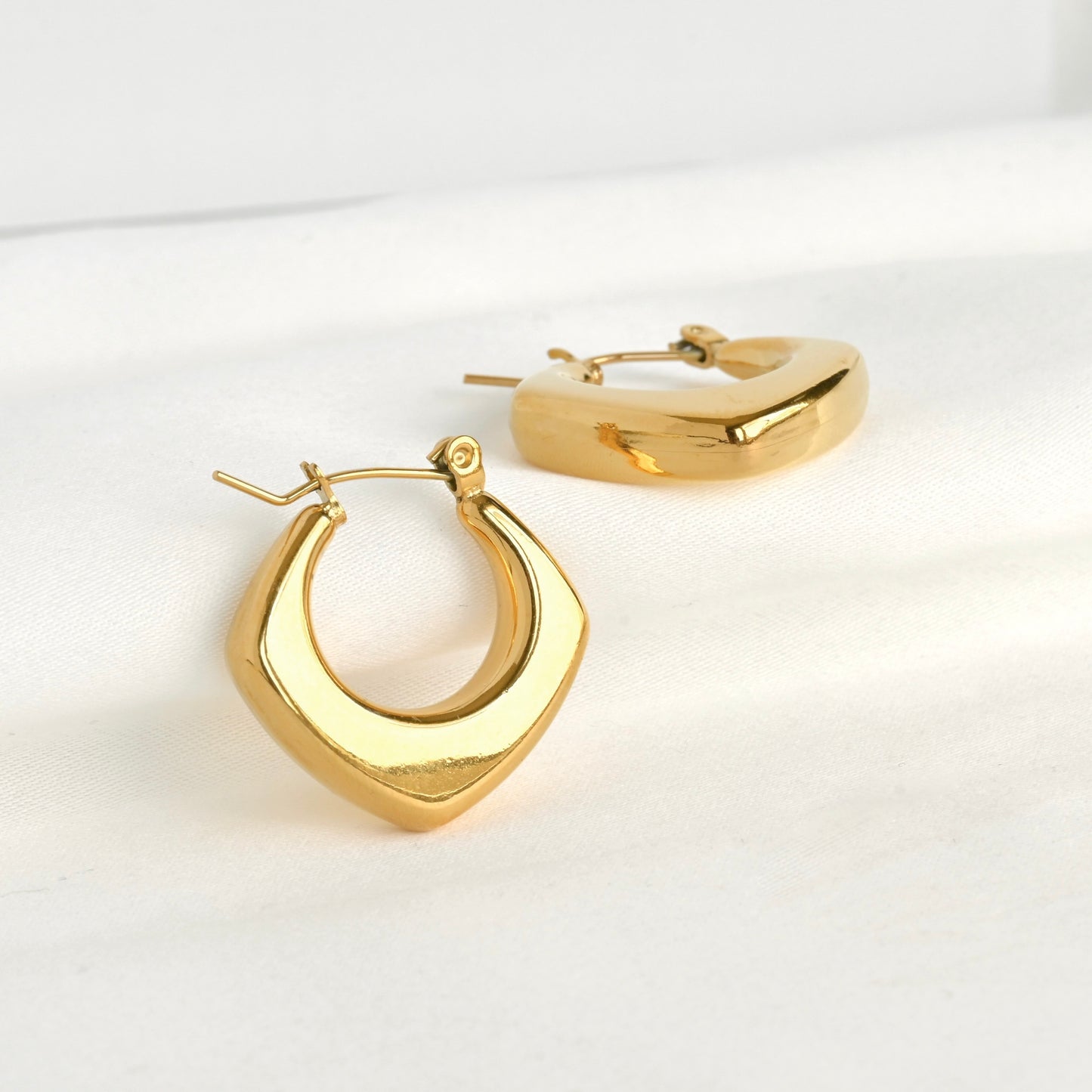 Bold diamond-shaped hoop earrings on a white background