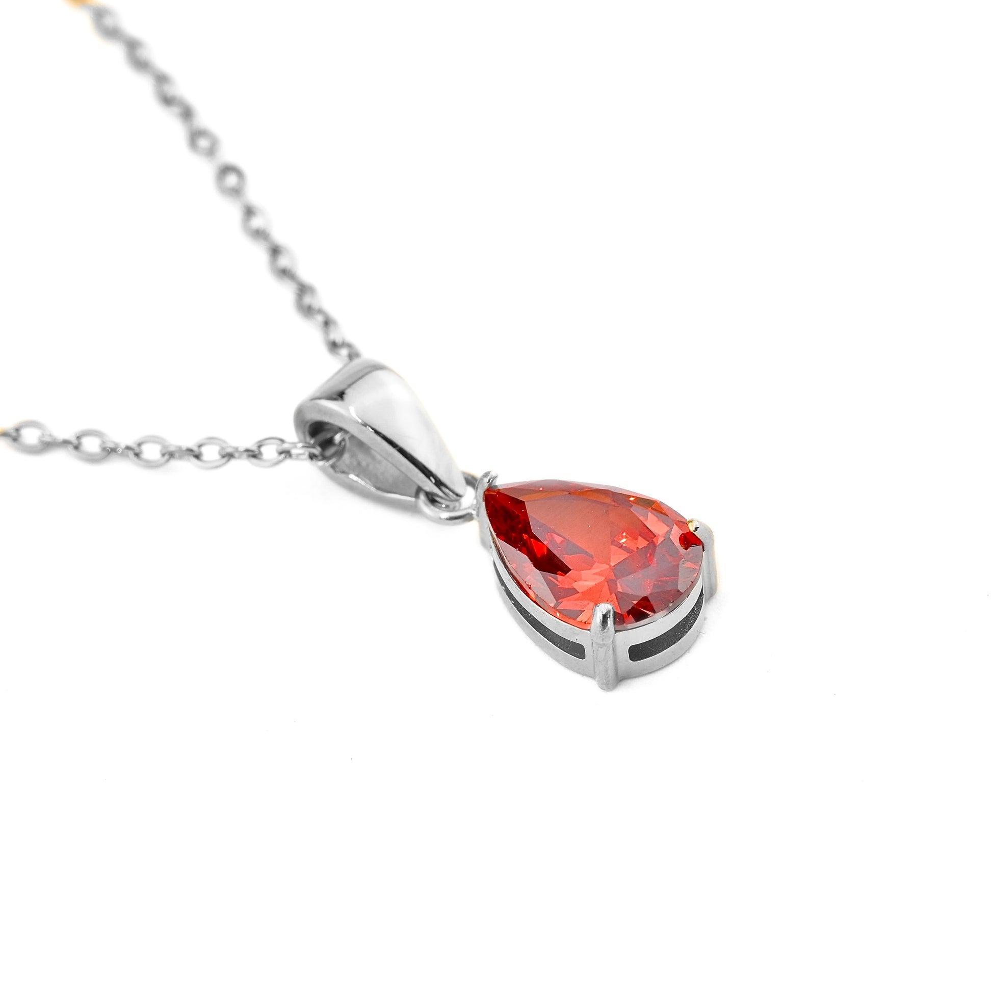 Silver necklace with a red teardrop pendant on a white background