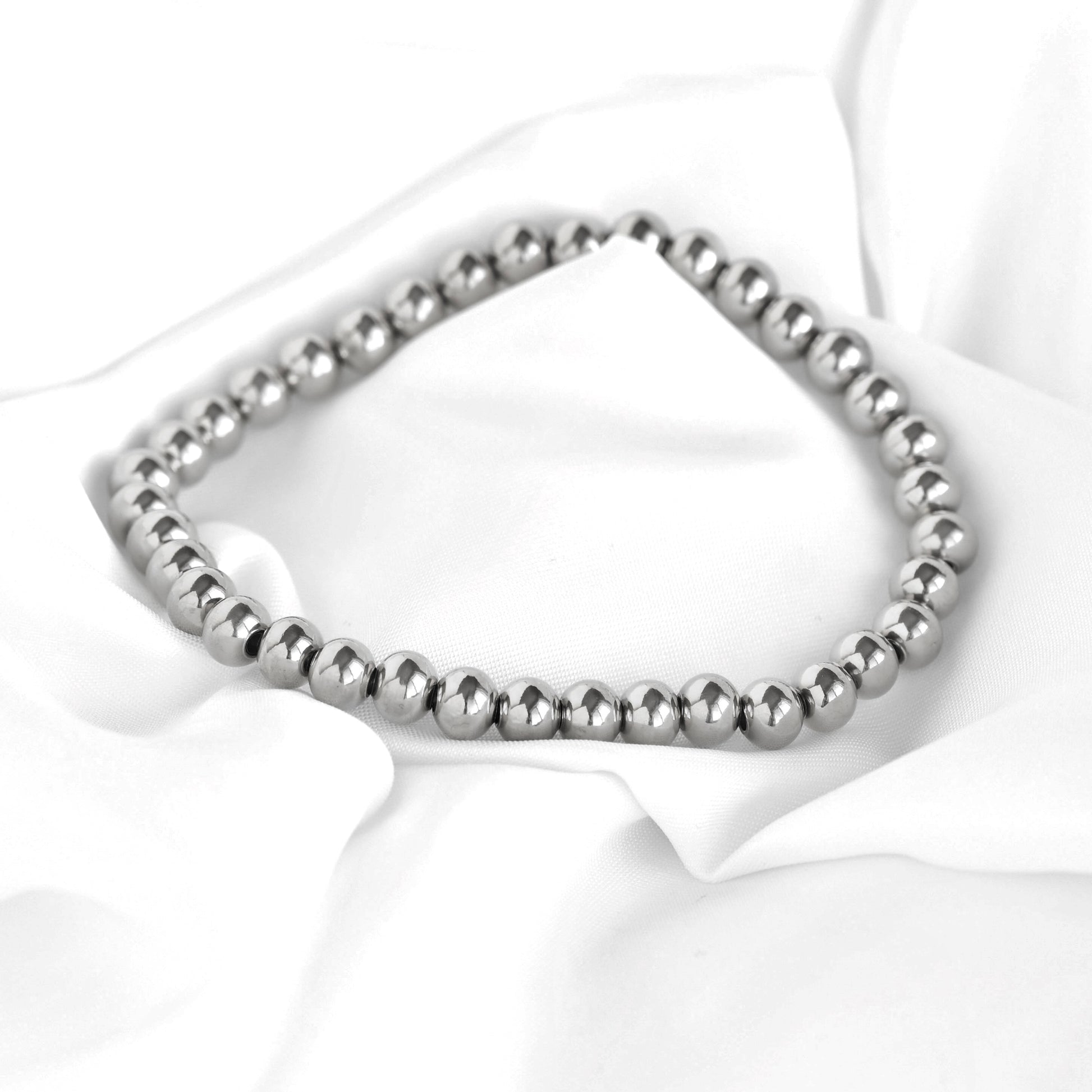 Silver beaded bracelet on a white fabric background