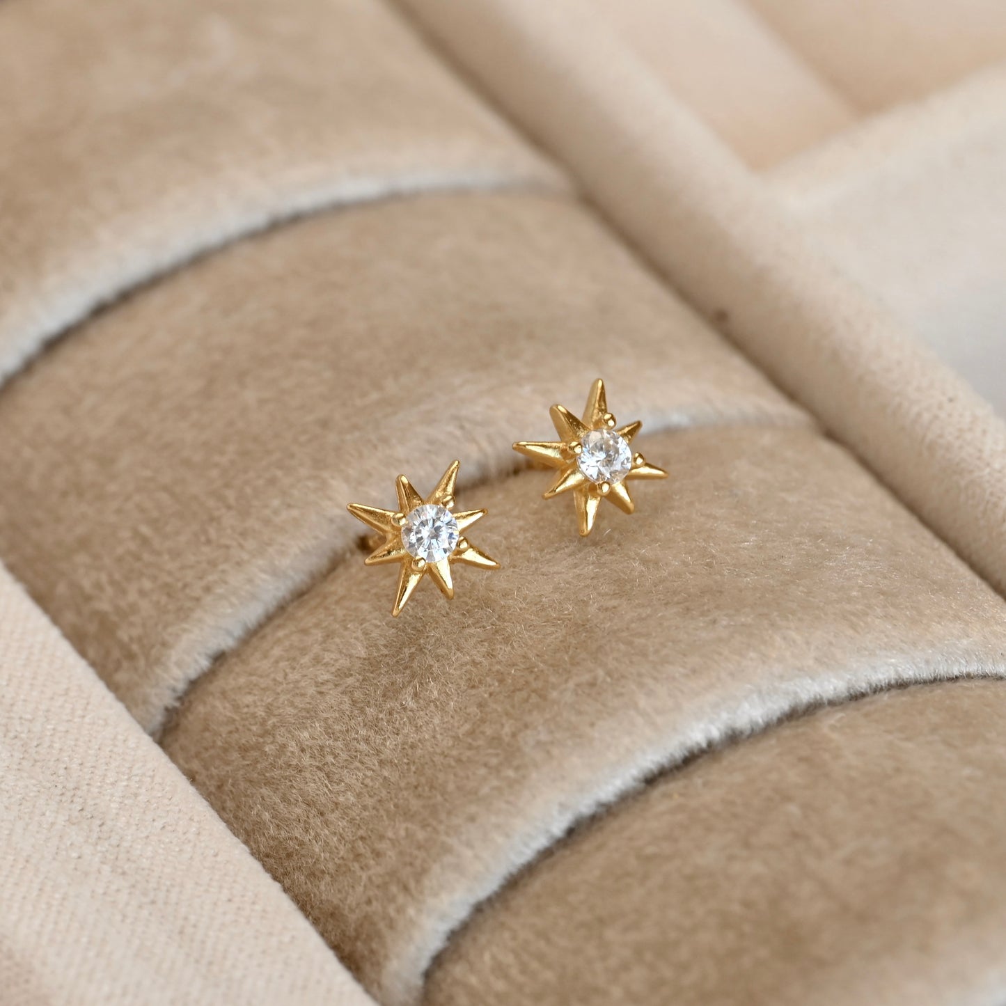 Gold north star studs on a beige fabric surface