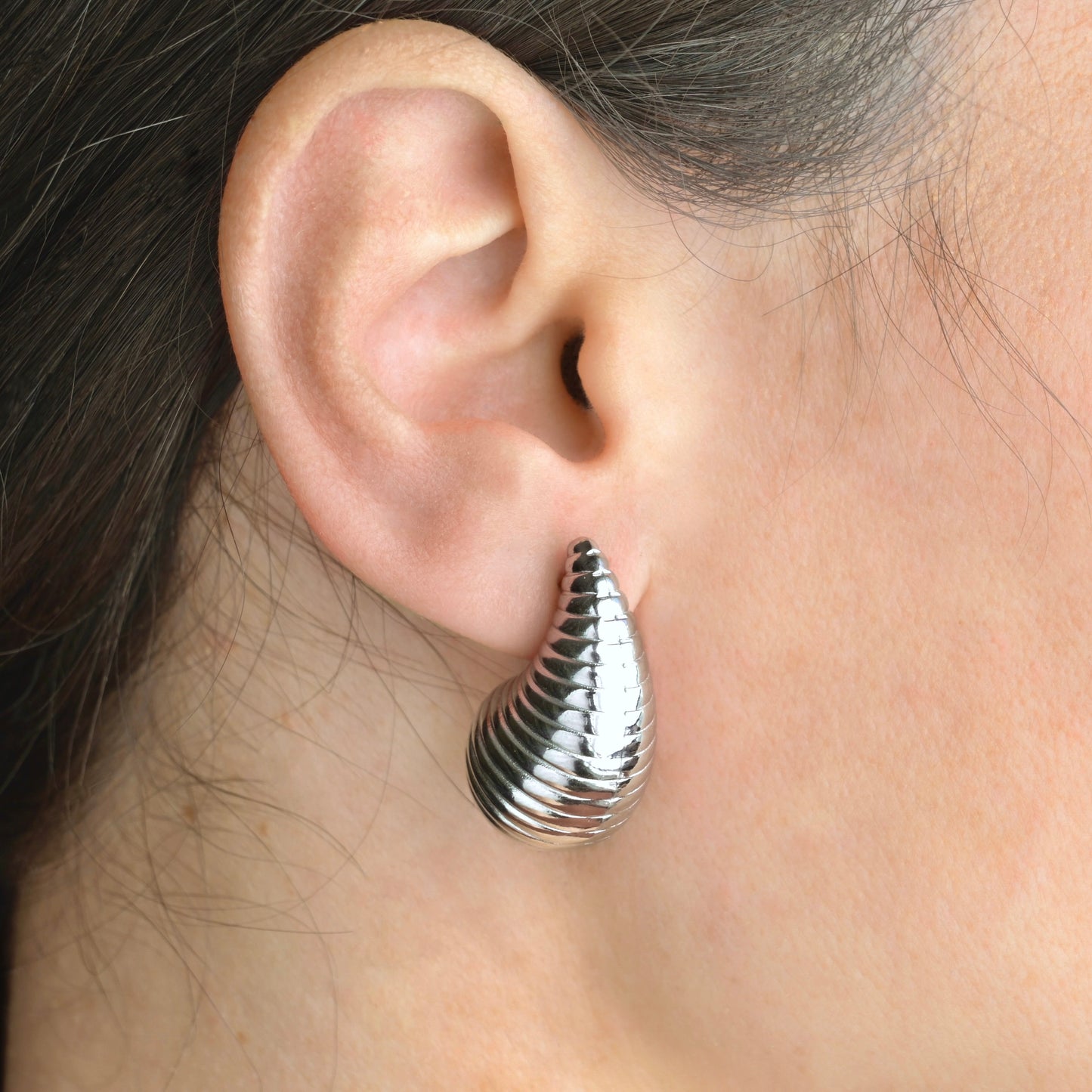 Bold silver statement earring worn on an ear