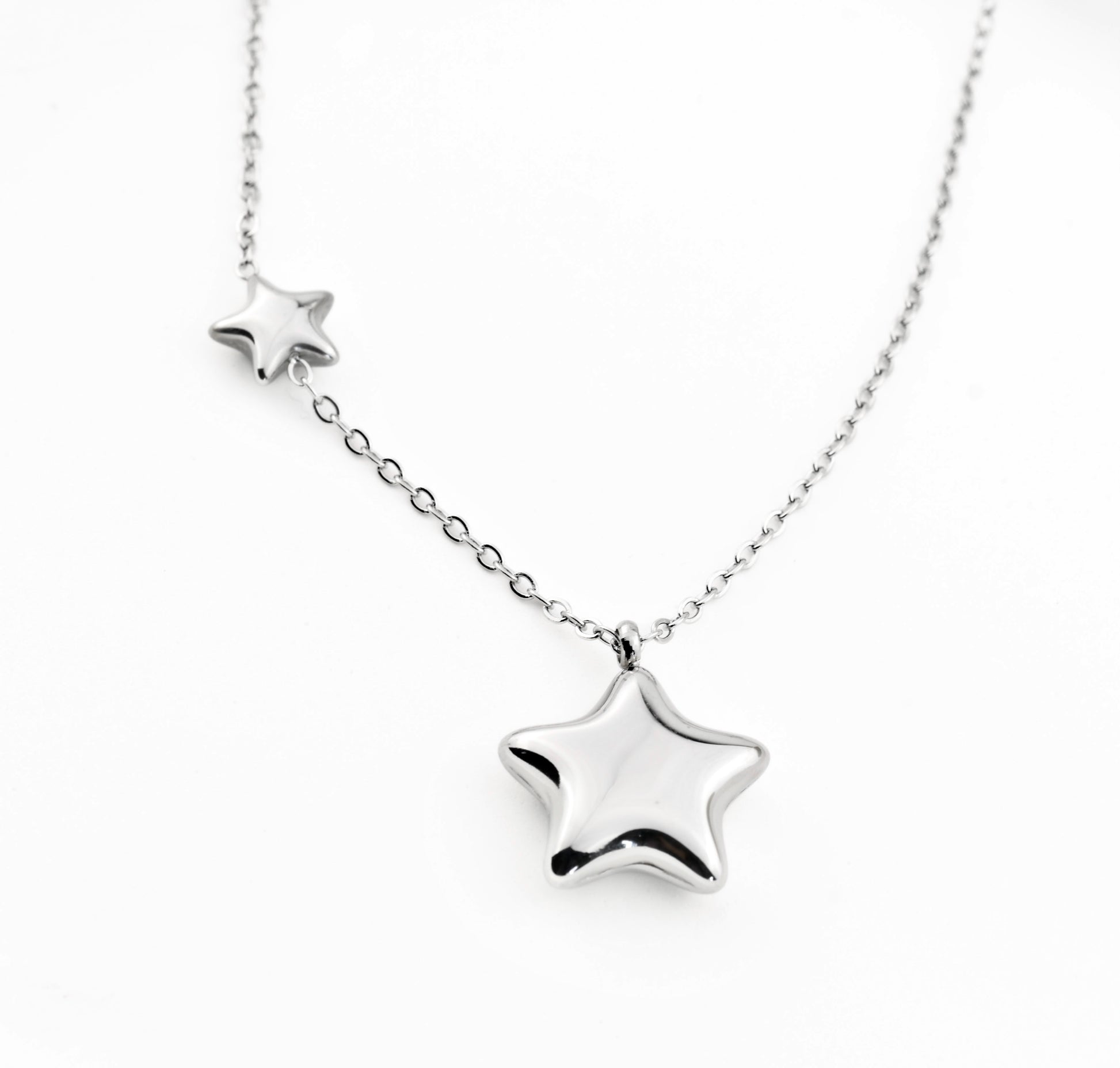 Silver star-shaped pendant on a chain against a white background