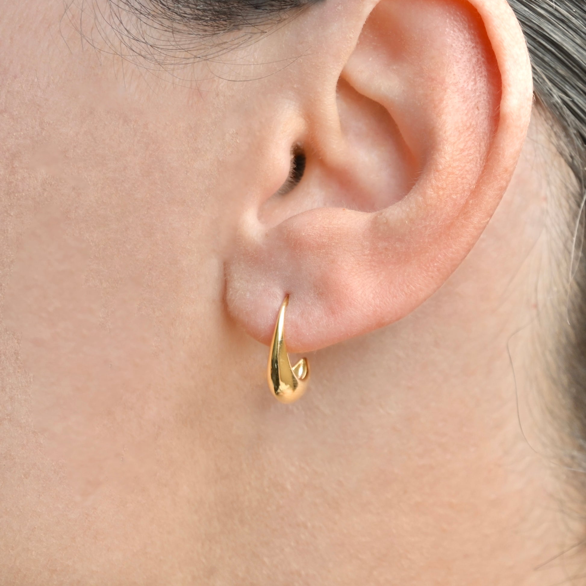 Small gold hoop earring worn by a person