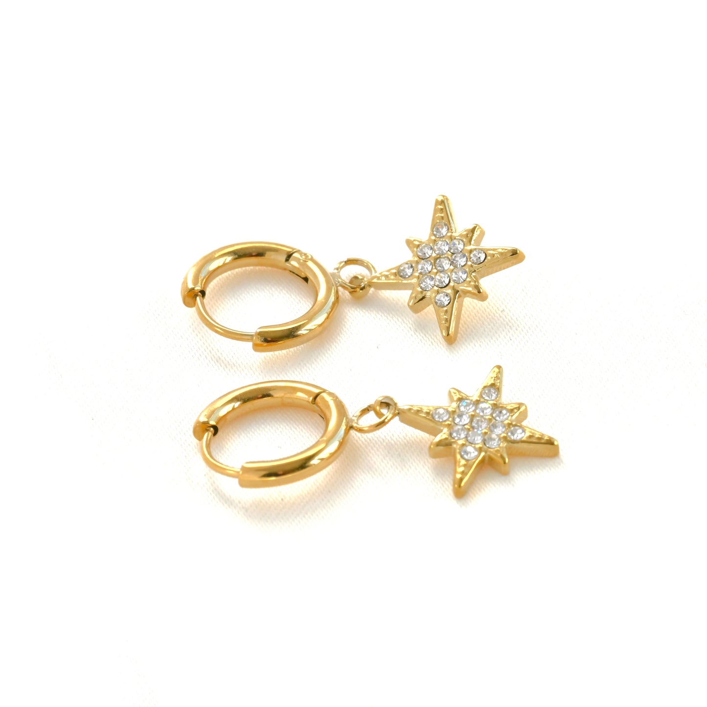 Gold star charm hoop earrings on white background