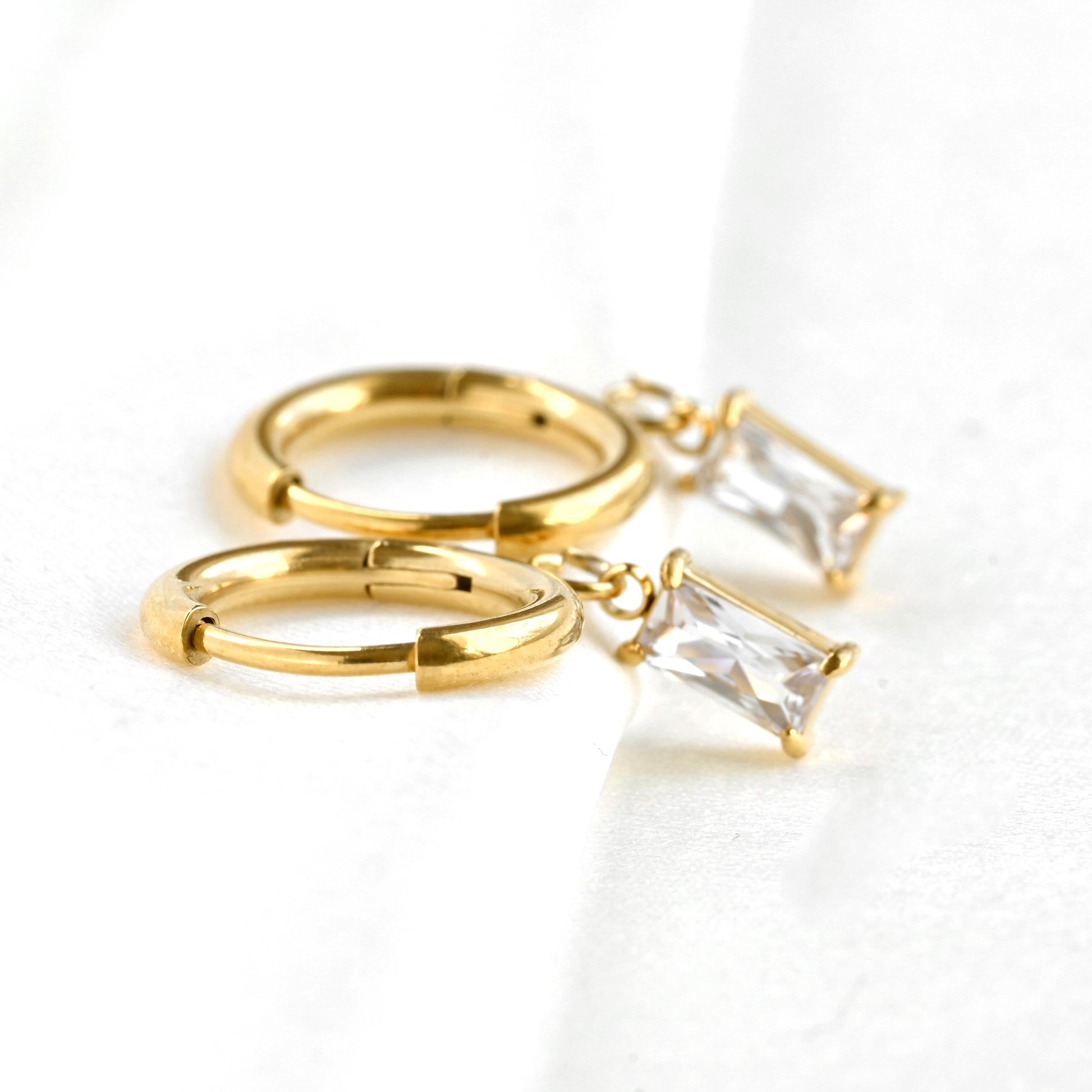 Gold hoop earrings with baguette cut stones on a white background