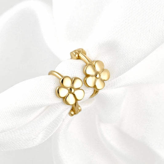 A pair of gold flower-shaped hoop earrings displayed on a soft white satin ribbon against a white background.