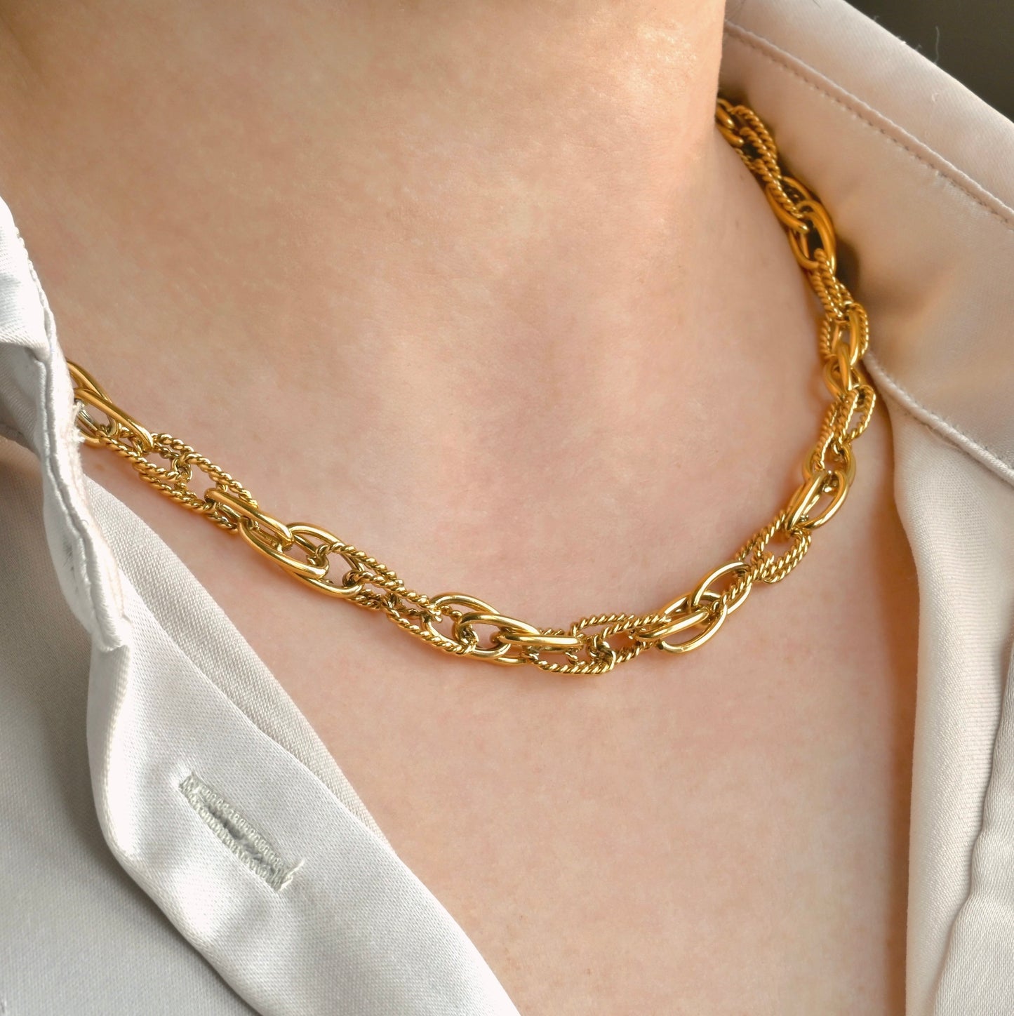 Gold oval links chain necklace worn by a person with a white shirt