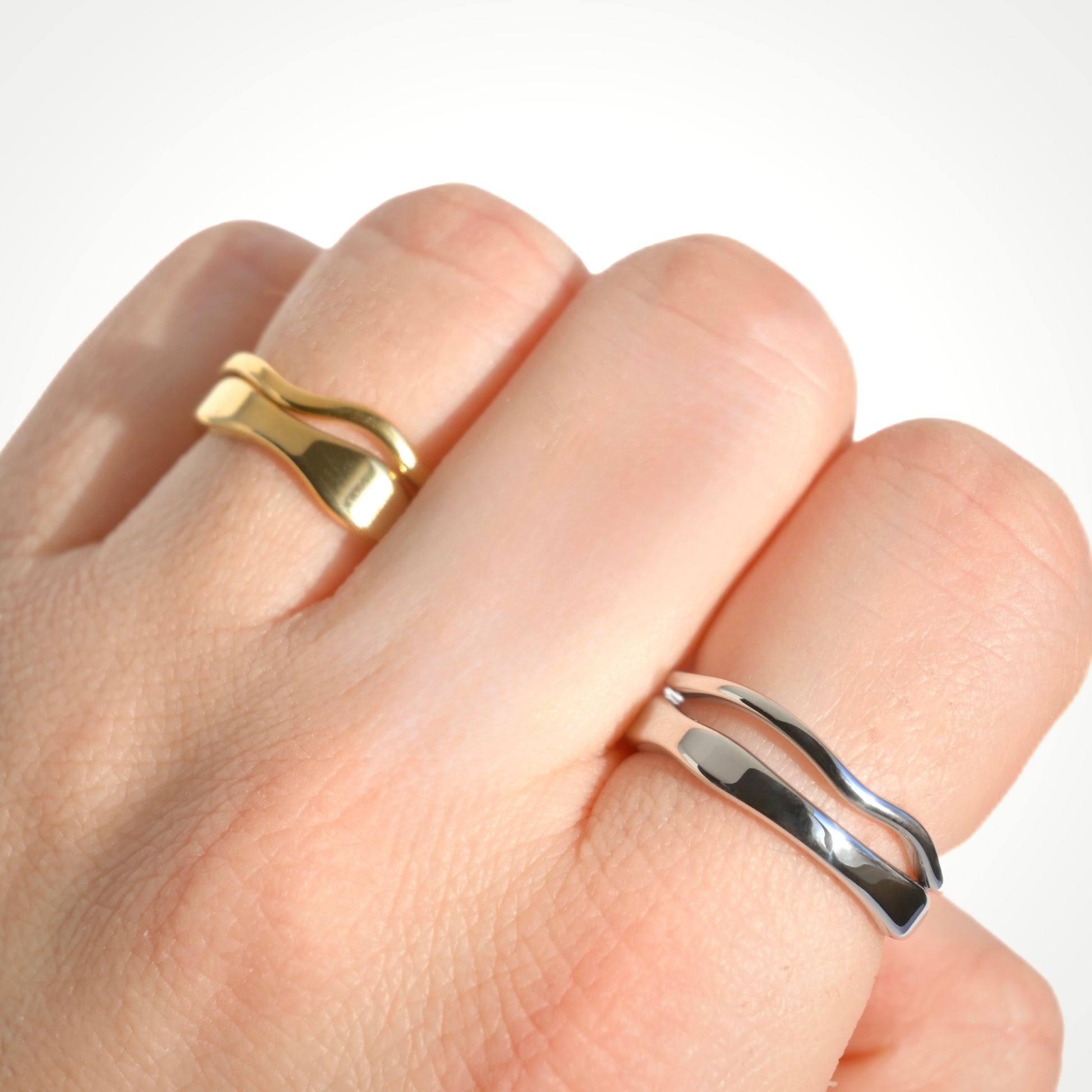 Gold and silver stacking rings on a hand against a white background