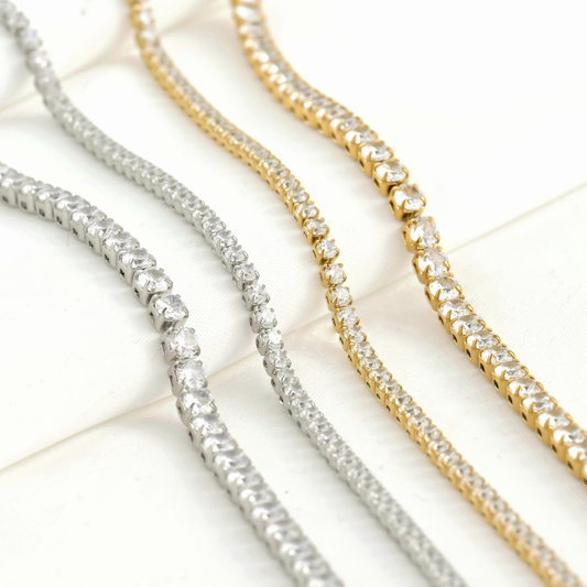Gold and silver tennis chain necklaces in 2 and 3mm widths on a light background