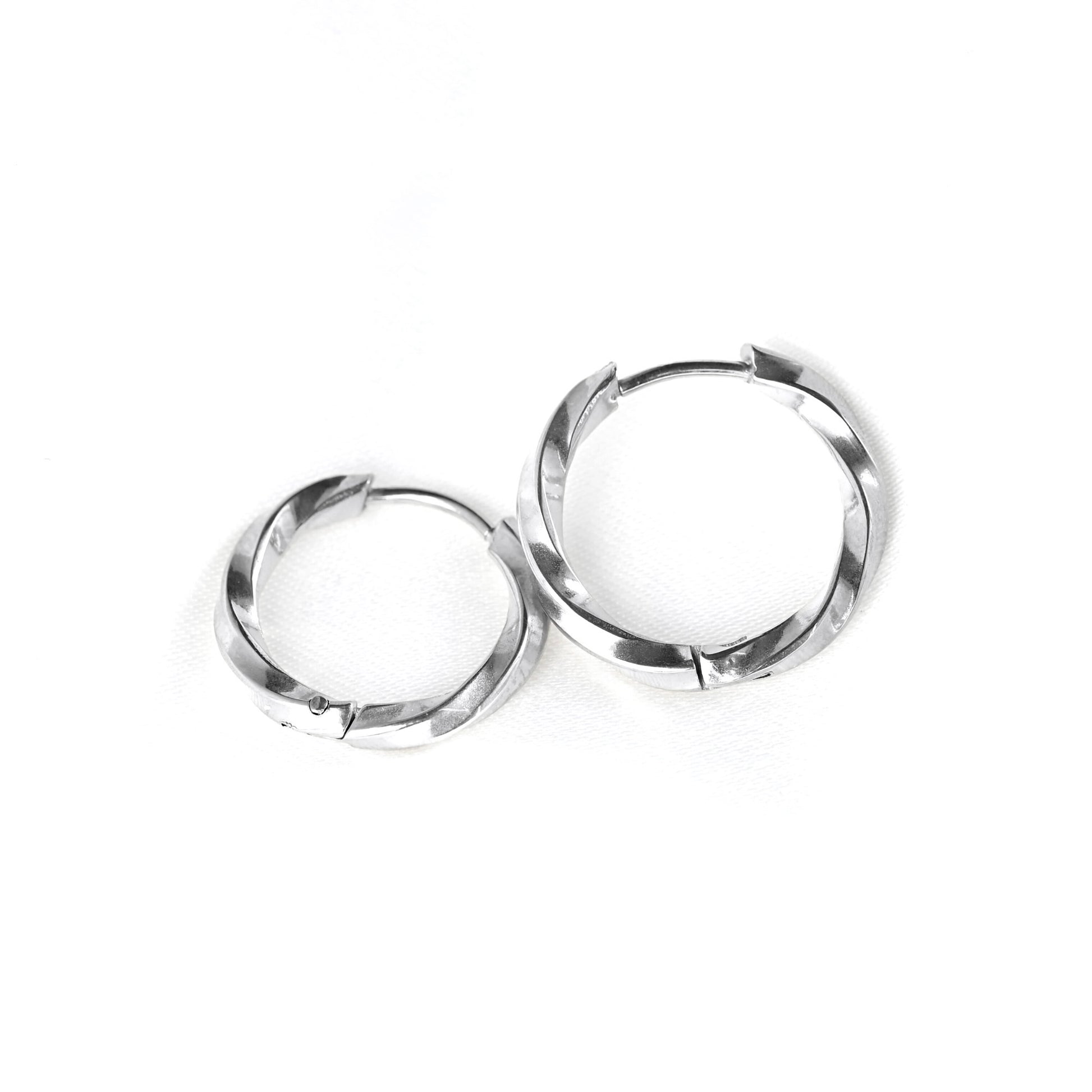 A pair of silver-toned hoop earrings with a textured, faceted outer edge, displayed on a clean white background.