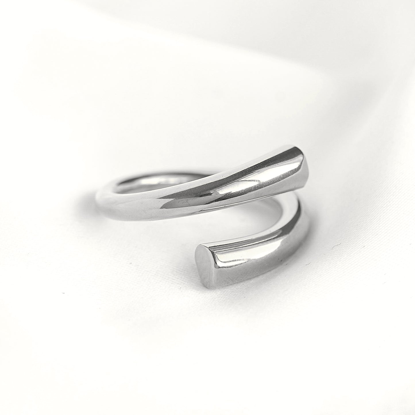 Close up view of a chunky silver open wrap ring on white surface