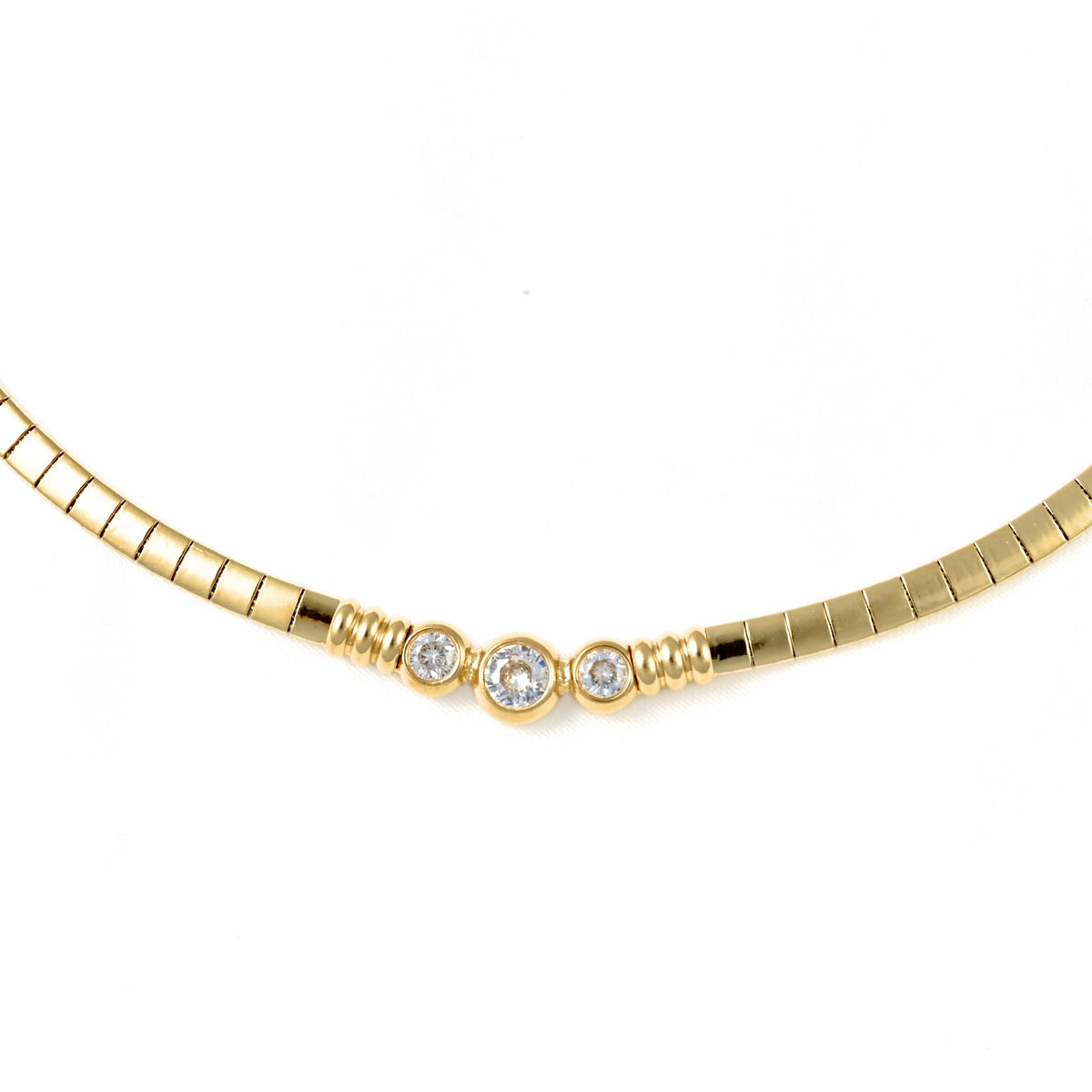 A gold snake chain necklace featuring three bezel-set round clear gemstones in the center, displayed against a solid white background.