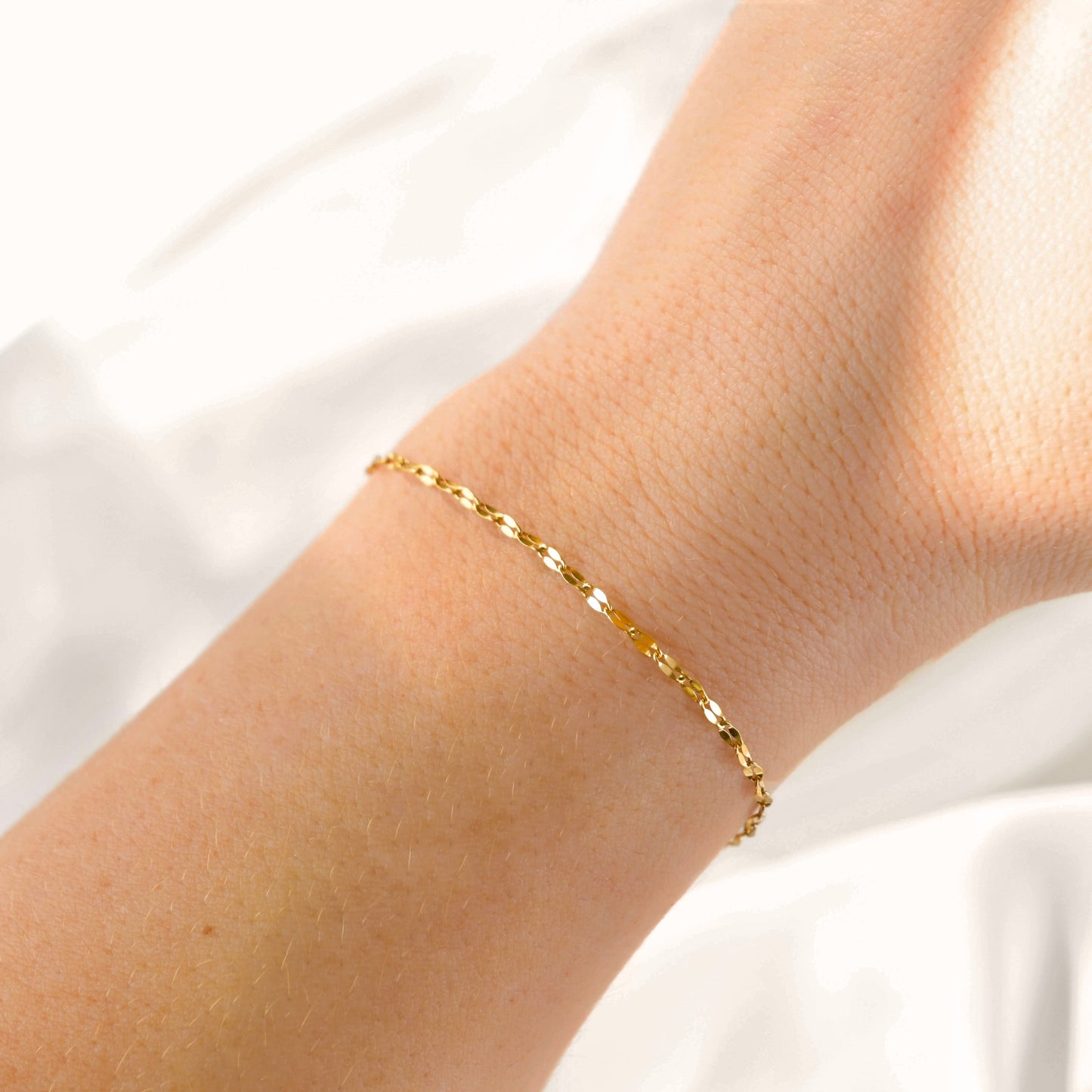 Delicated Gold bracelet on a person's wrist against a white background