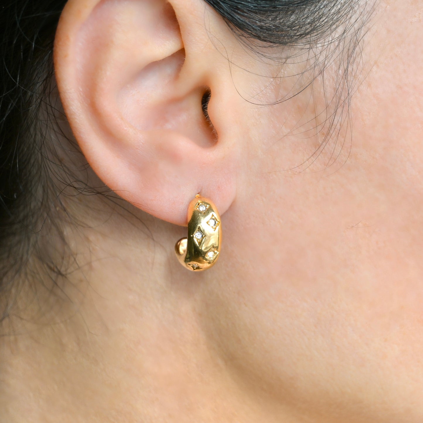 Gold diamond hoop earrings worn by a person