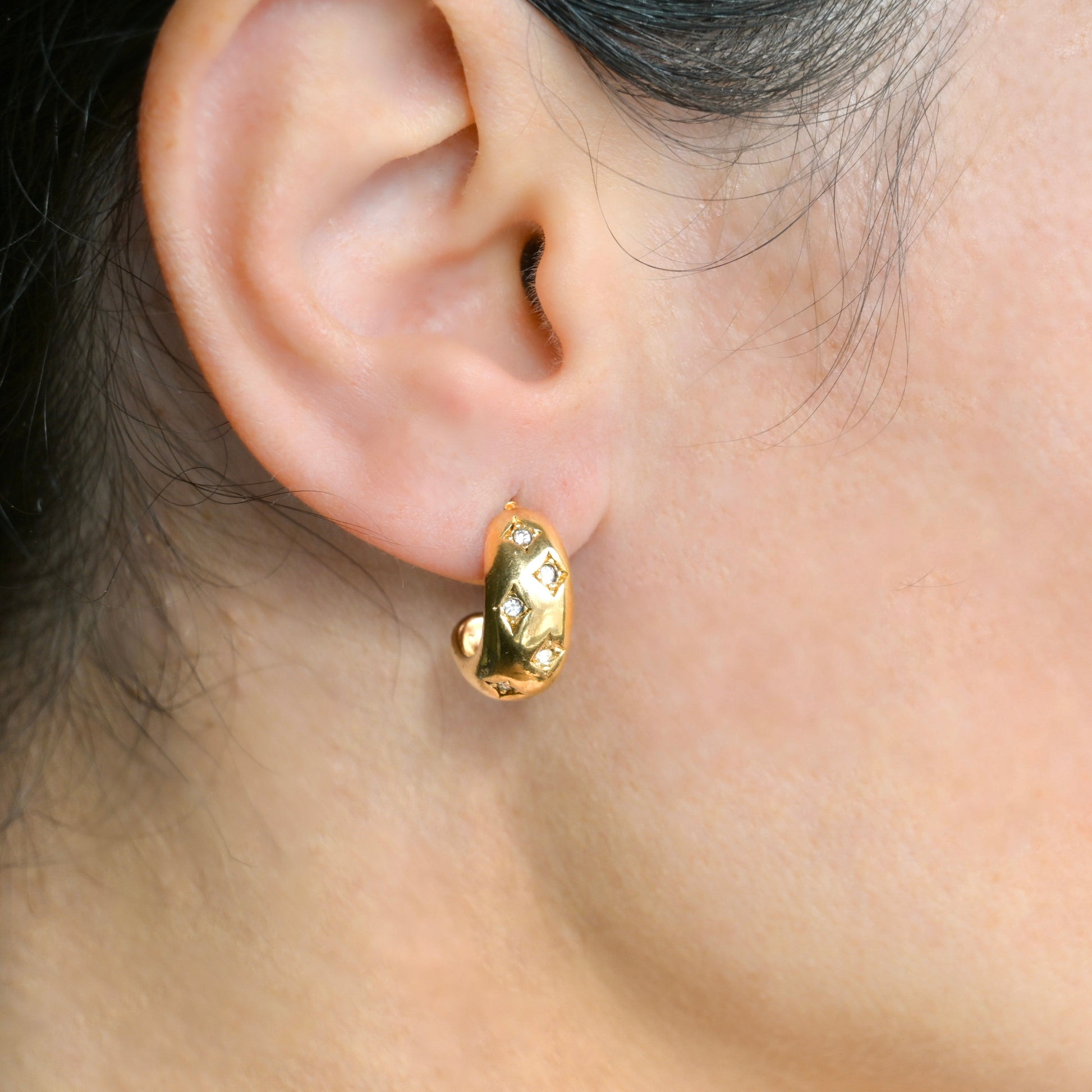 Gold diamond hoop earrings worn by a person