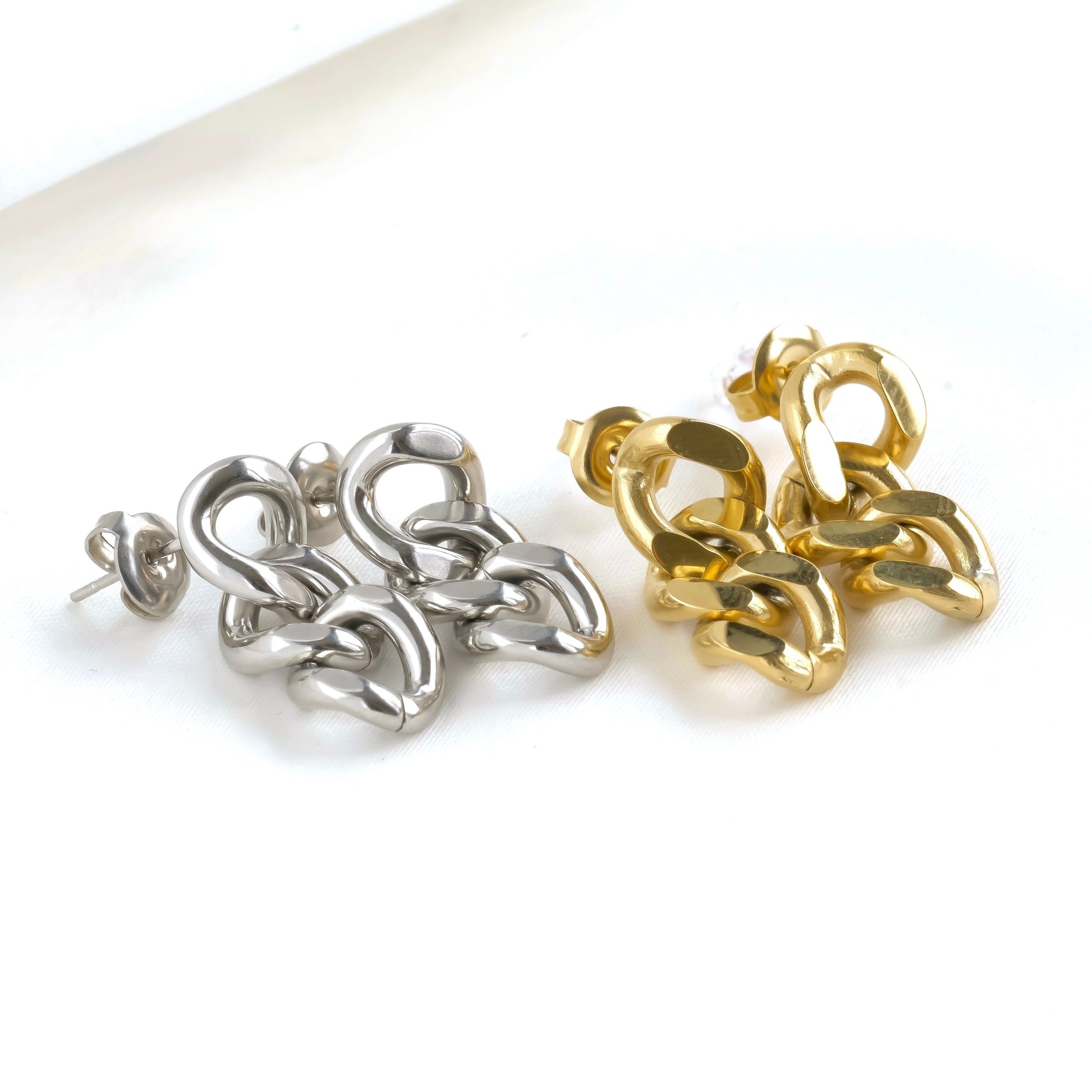 Pair of silver and gold chain-style earrings on a white background