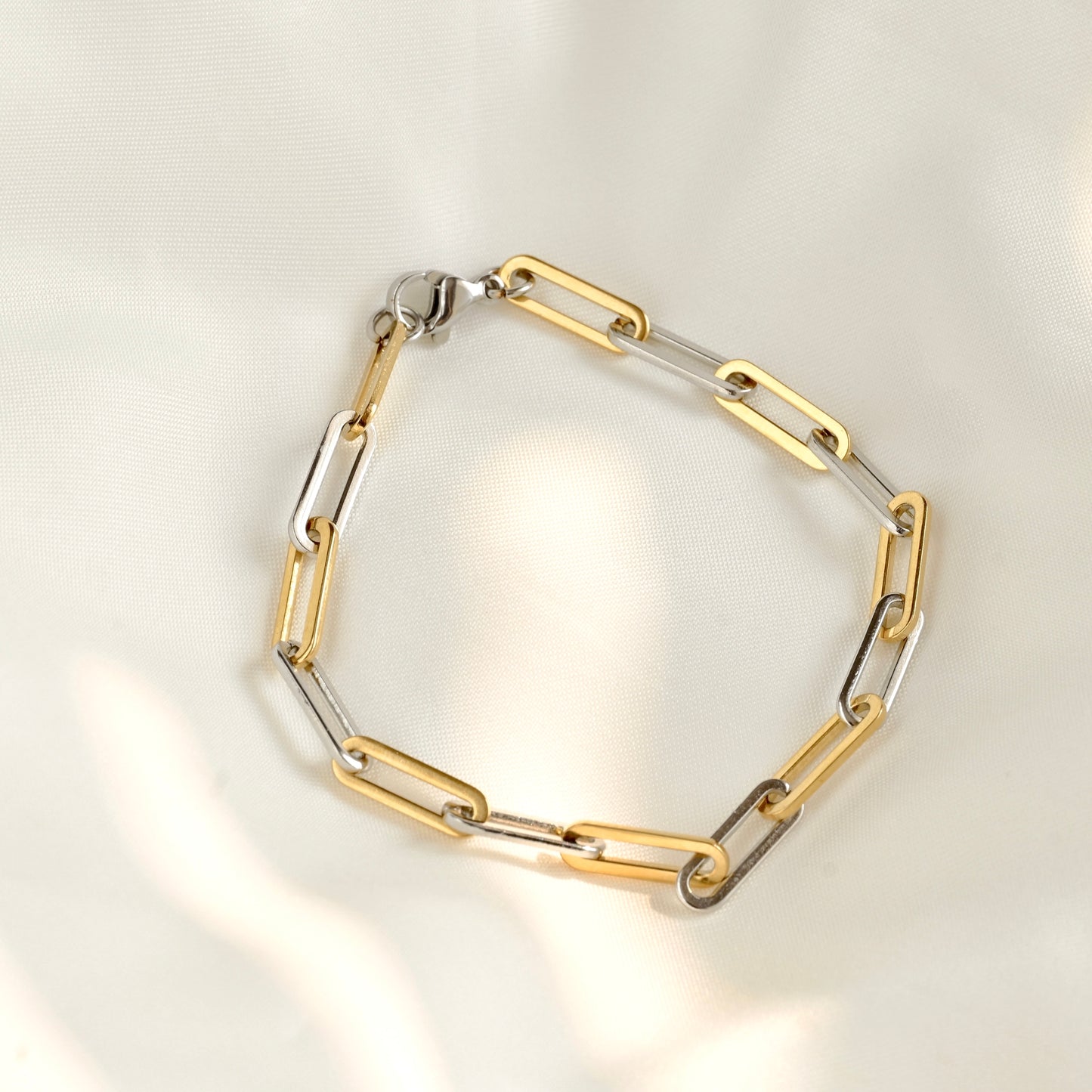 Gold and silver chain bracelet on a light gray background