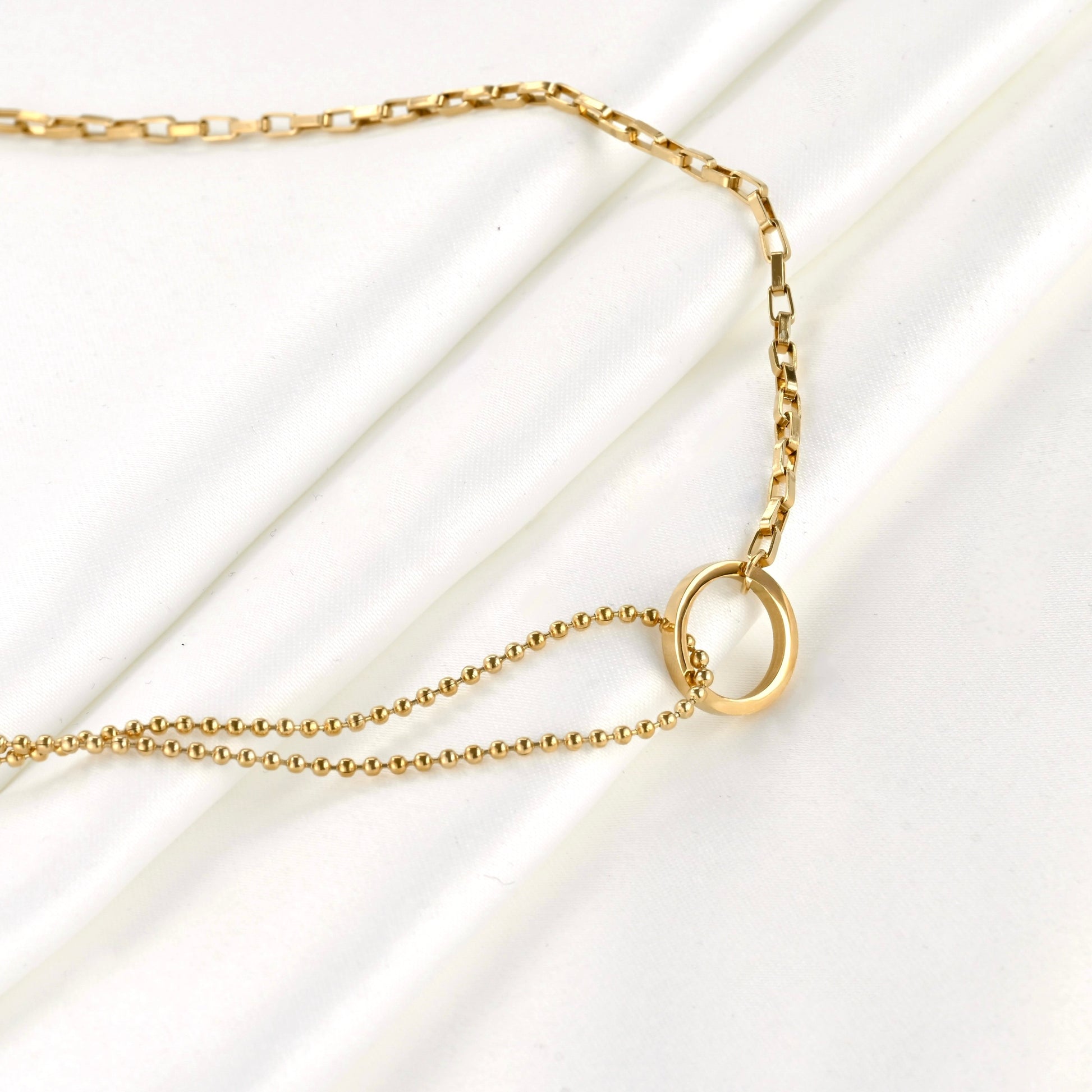 Gold mixed chain necklace with a small circle link pendant on a white background