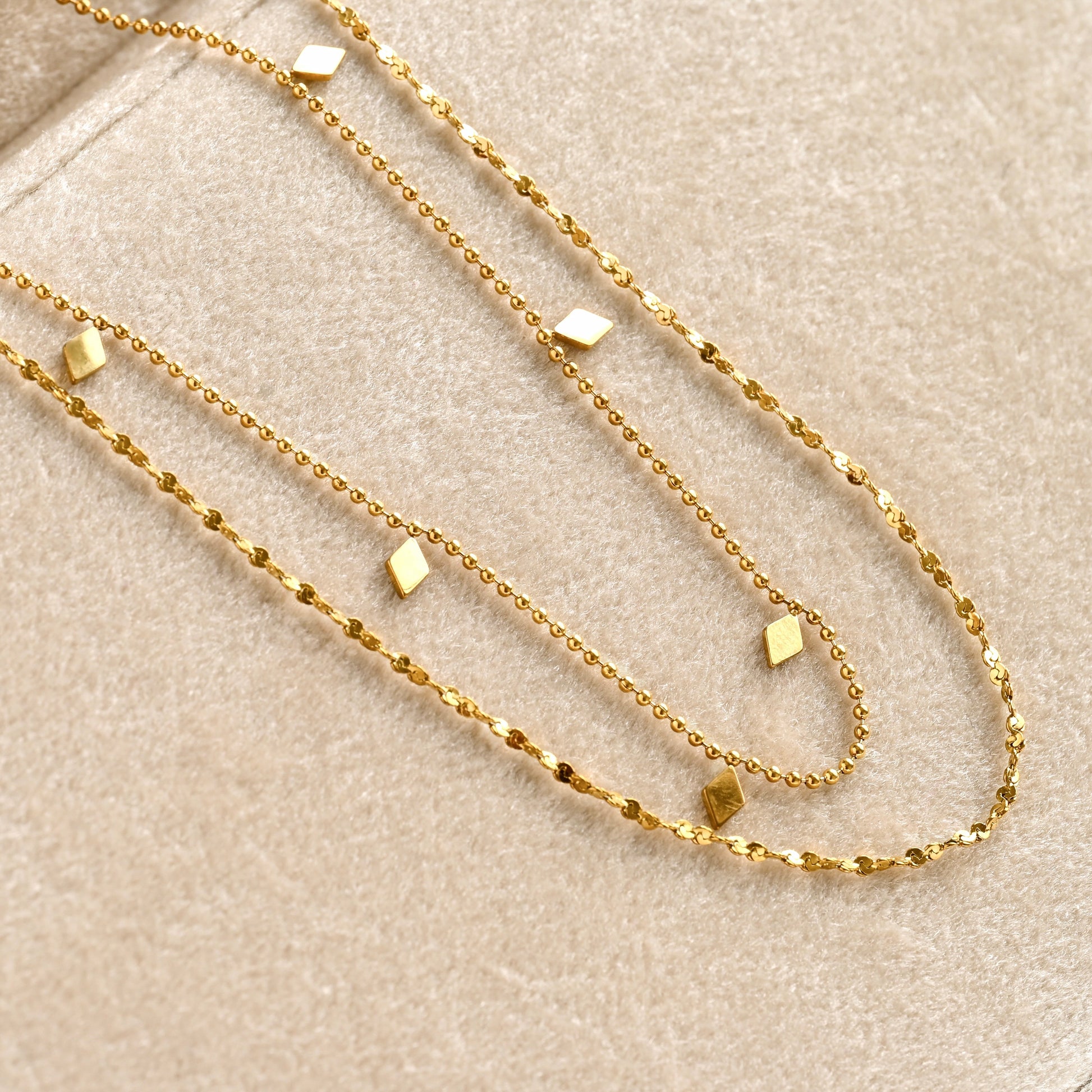 Gold chain necklace set on a beige velvet surface