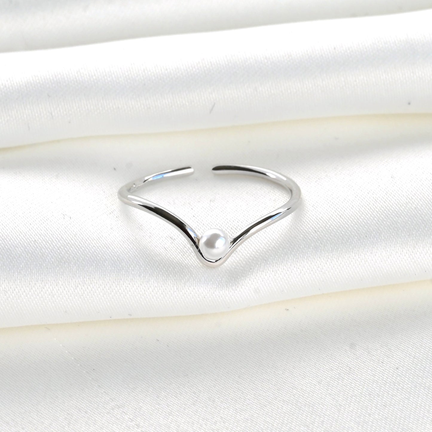 Silver ring with a pearl on a white satin background