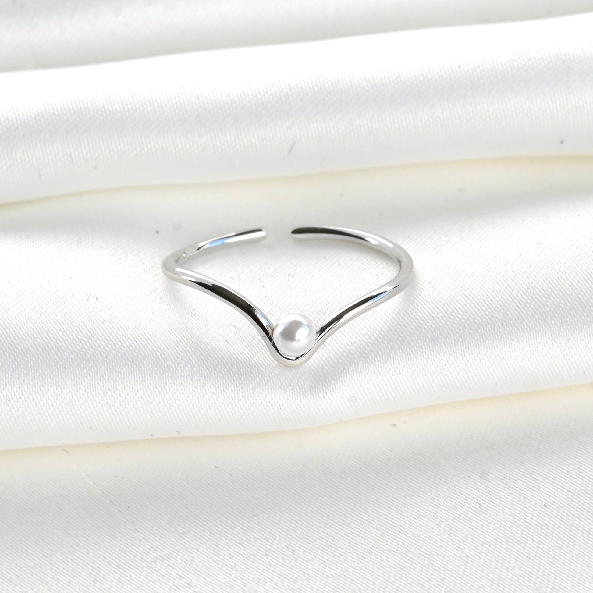 Silver ring with a pearl on a white satin background