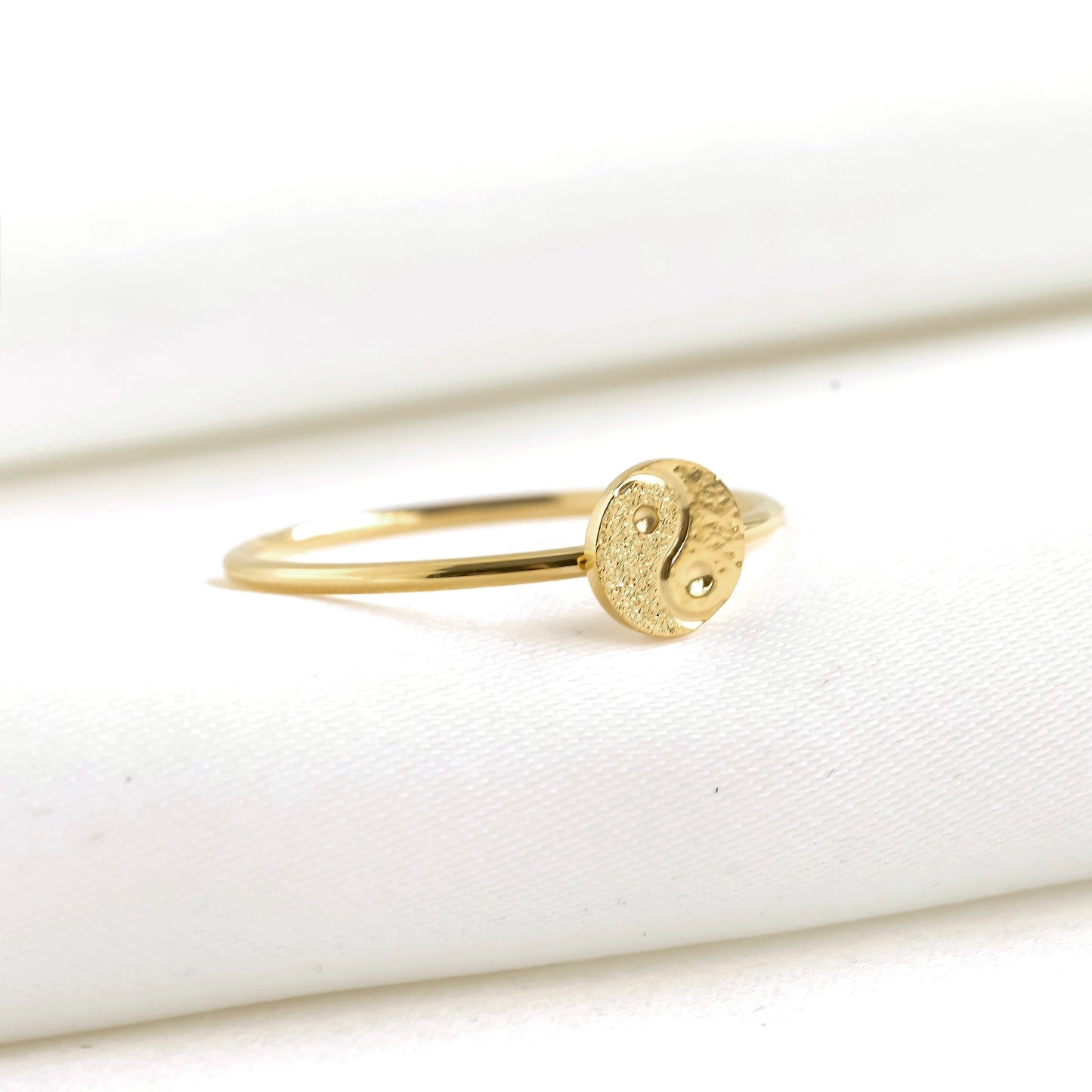 Gold ring with a yin yang symbol on a white background