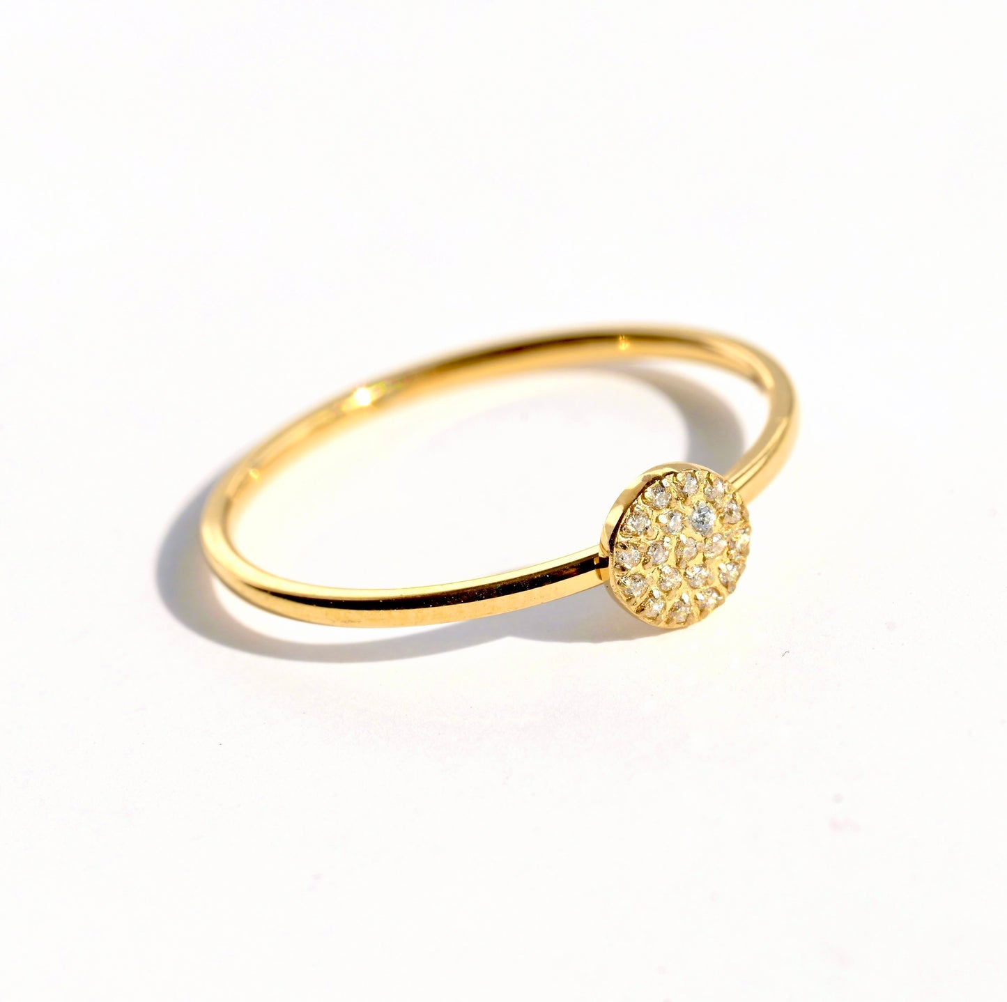 Angled view of gold pave coin ring on a white background