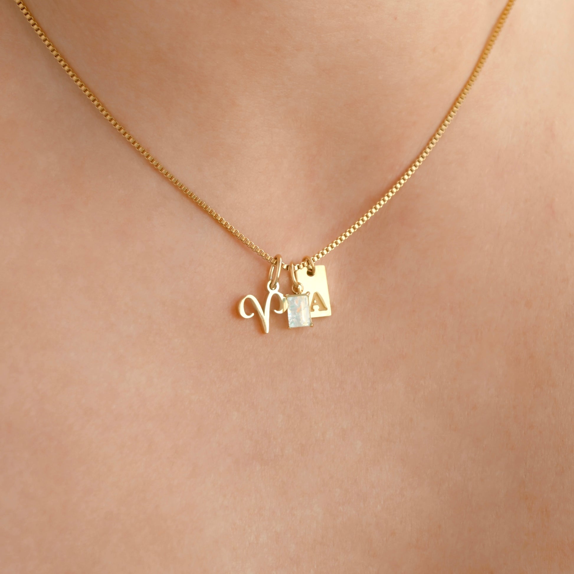 Dainty gold chain necklace with charms on a person's neck against a neutral background