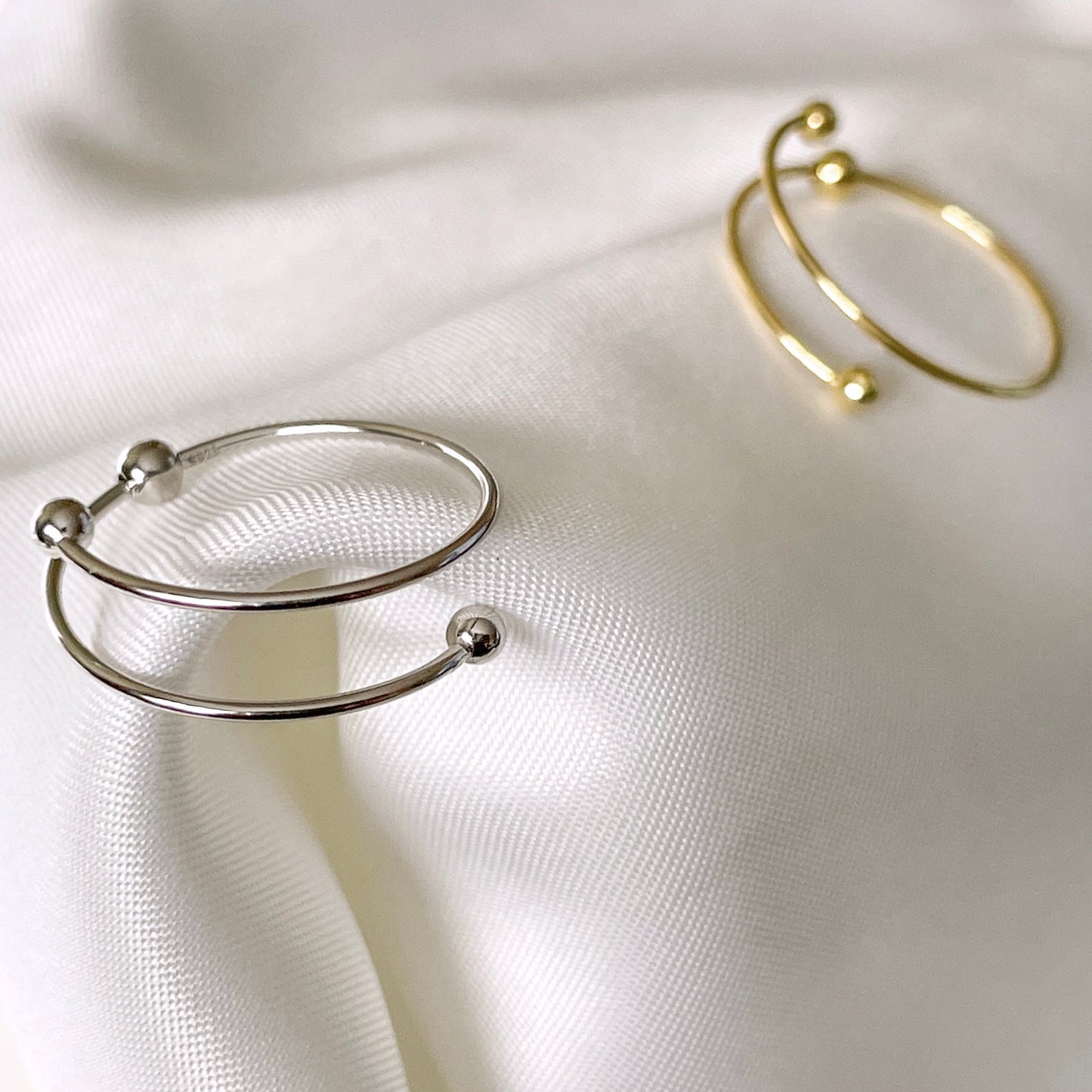 Gold and silver fidgeting rings with beads on a white fabric background