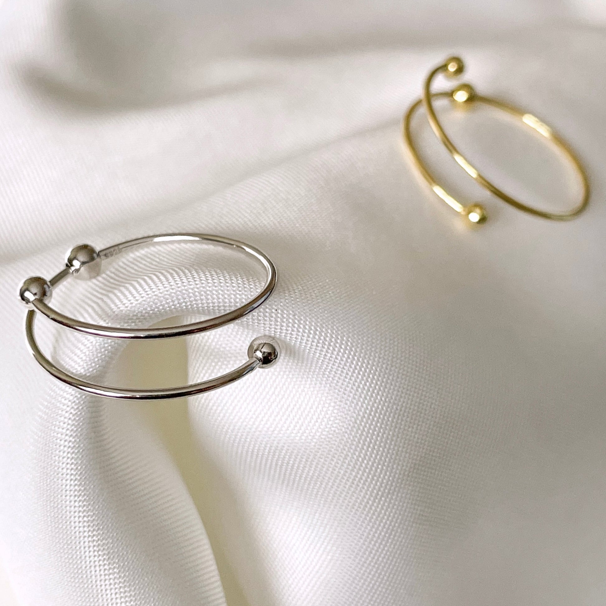 Gold and silver fidgeting rings with beads on a white fabric background